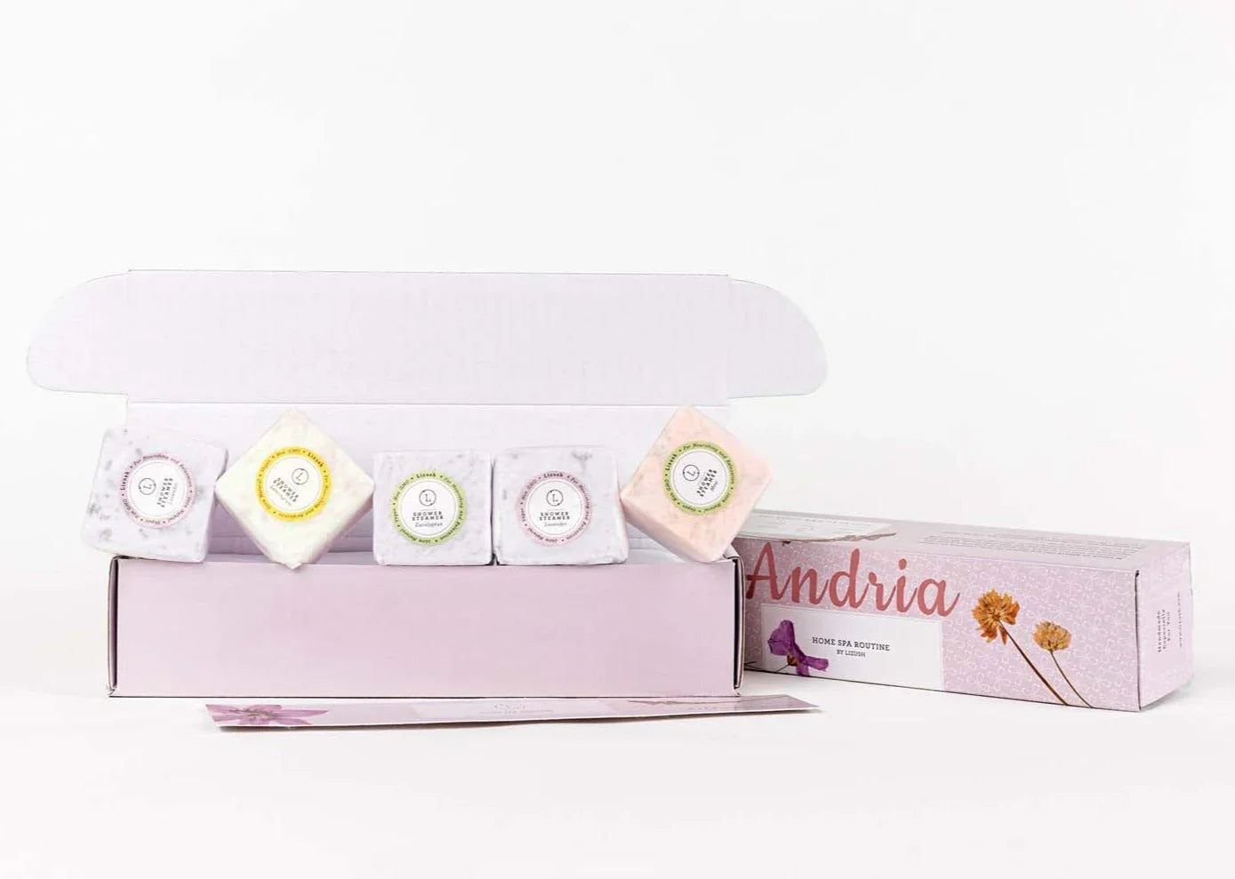 Open pink box with assorted colorful shower steamers labeled with scents and floral packaging