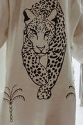 Close-up of beige fabric with black graphic print of a walking leopard and palm tree designs