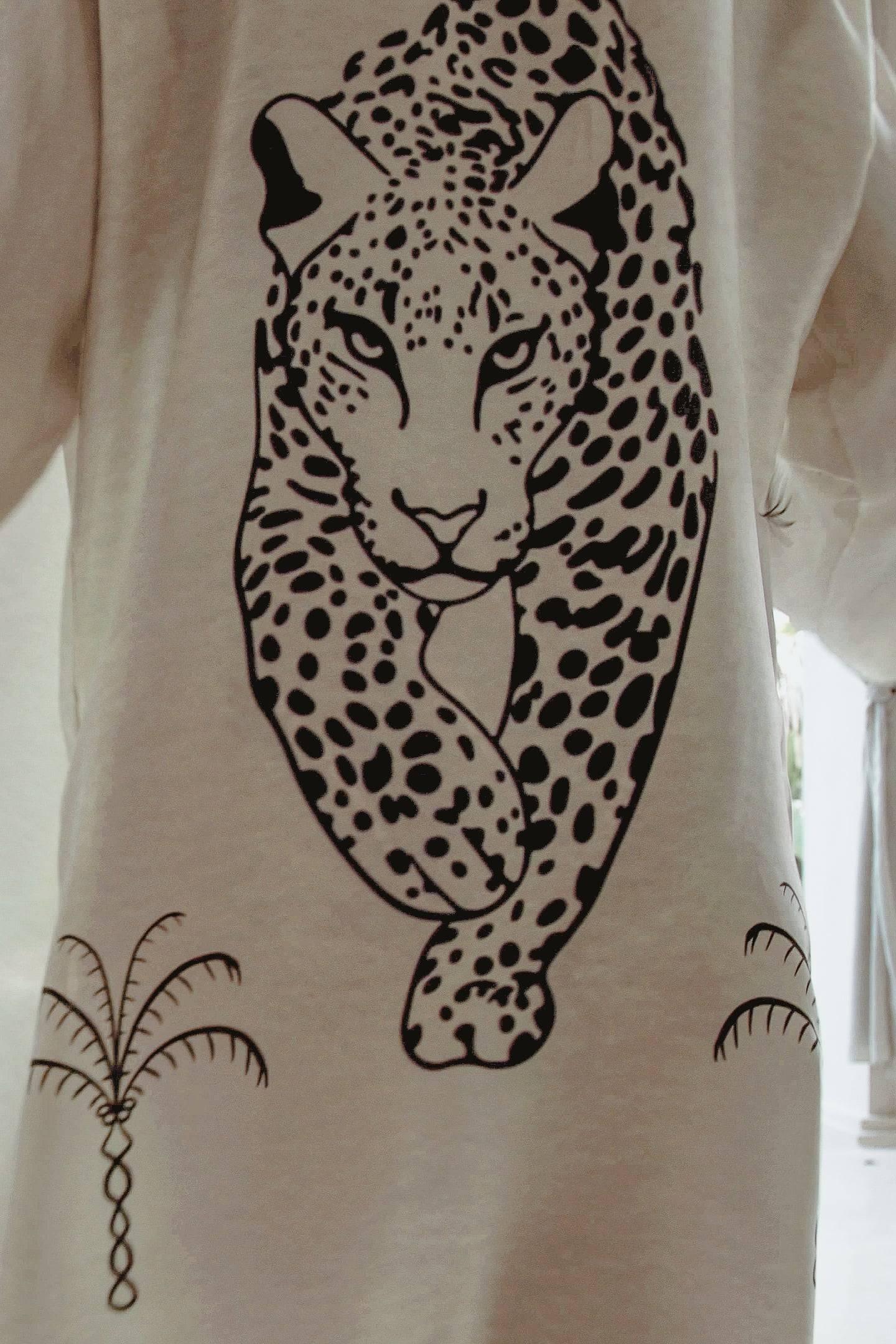 Close-up of beige fabric with black graphic print of a walking leopard and palm tree designs