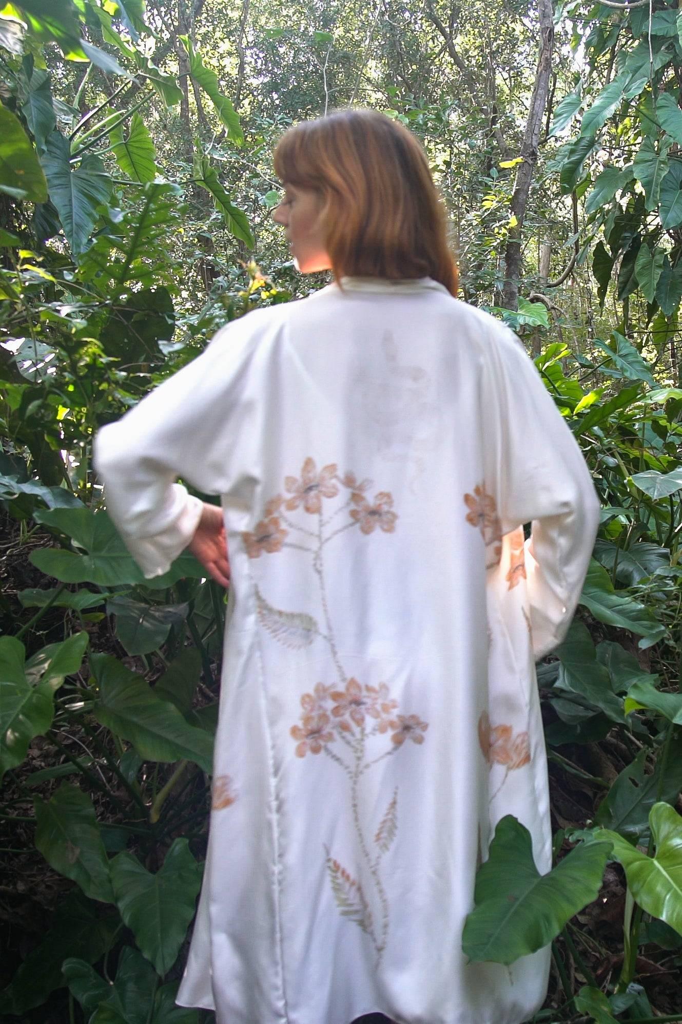 Woman with red hair wearing a white floral kimono in a lush green forest environment