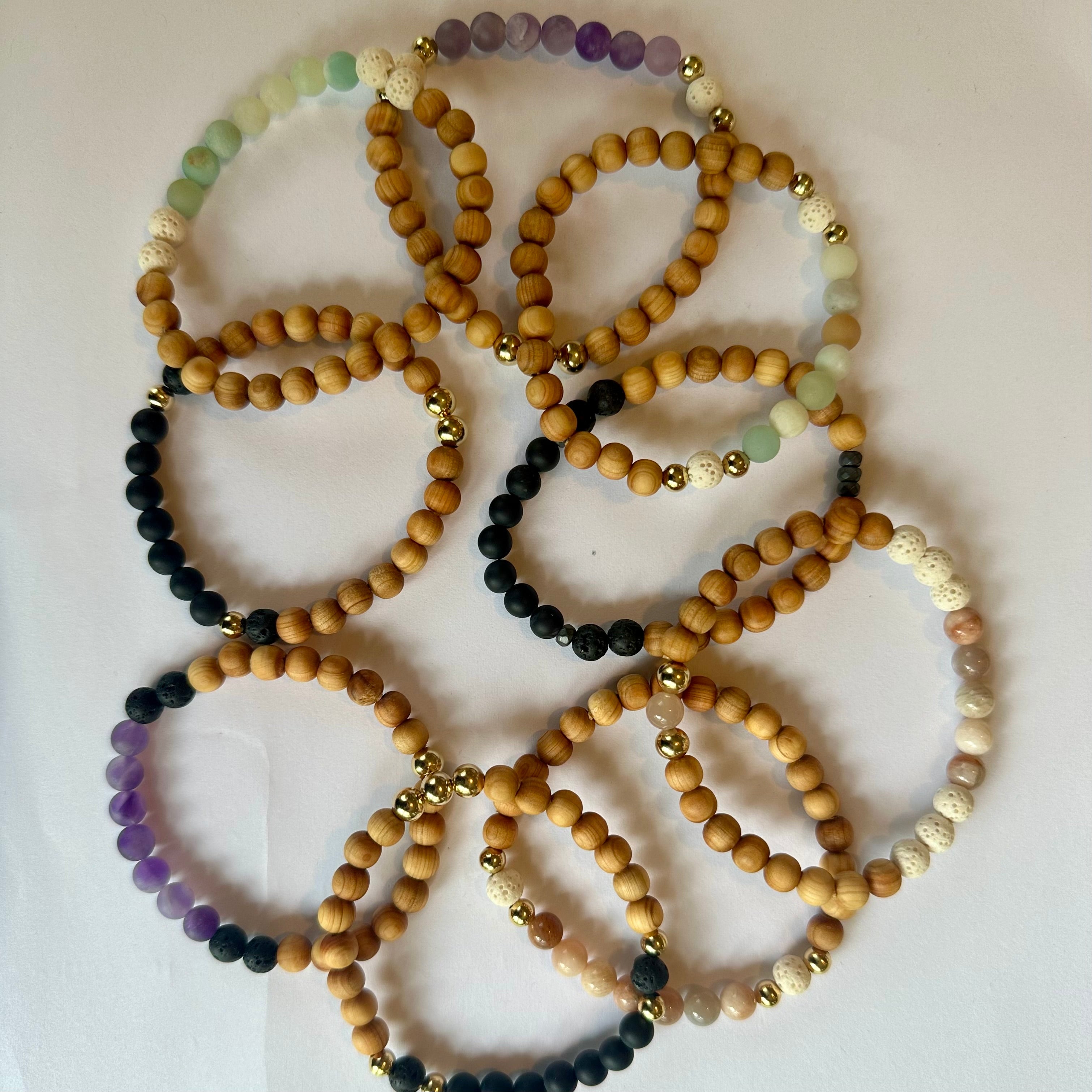 Handmade beaded bracelets with wooden, colorful gemstone, lava, and gold accent beads on white background