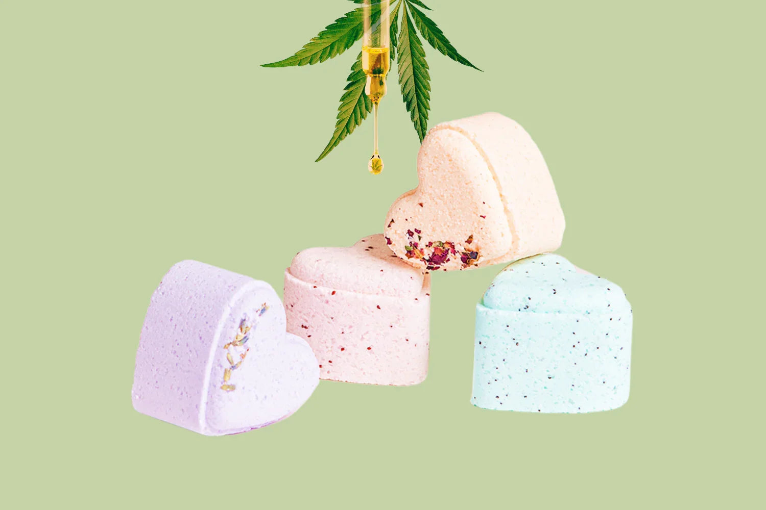 Heart-shaped pastel bath bombs with herbs and CBD oil dropper with cannabis leaves on green background