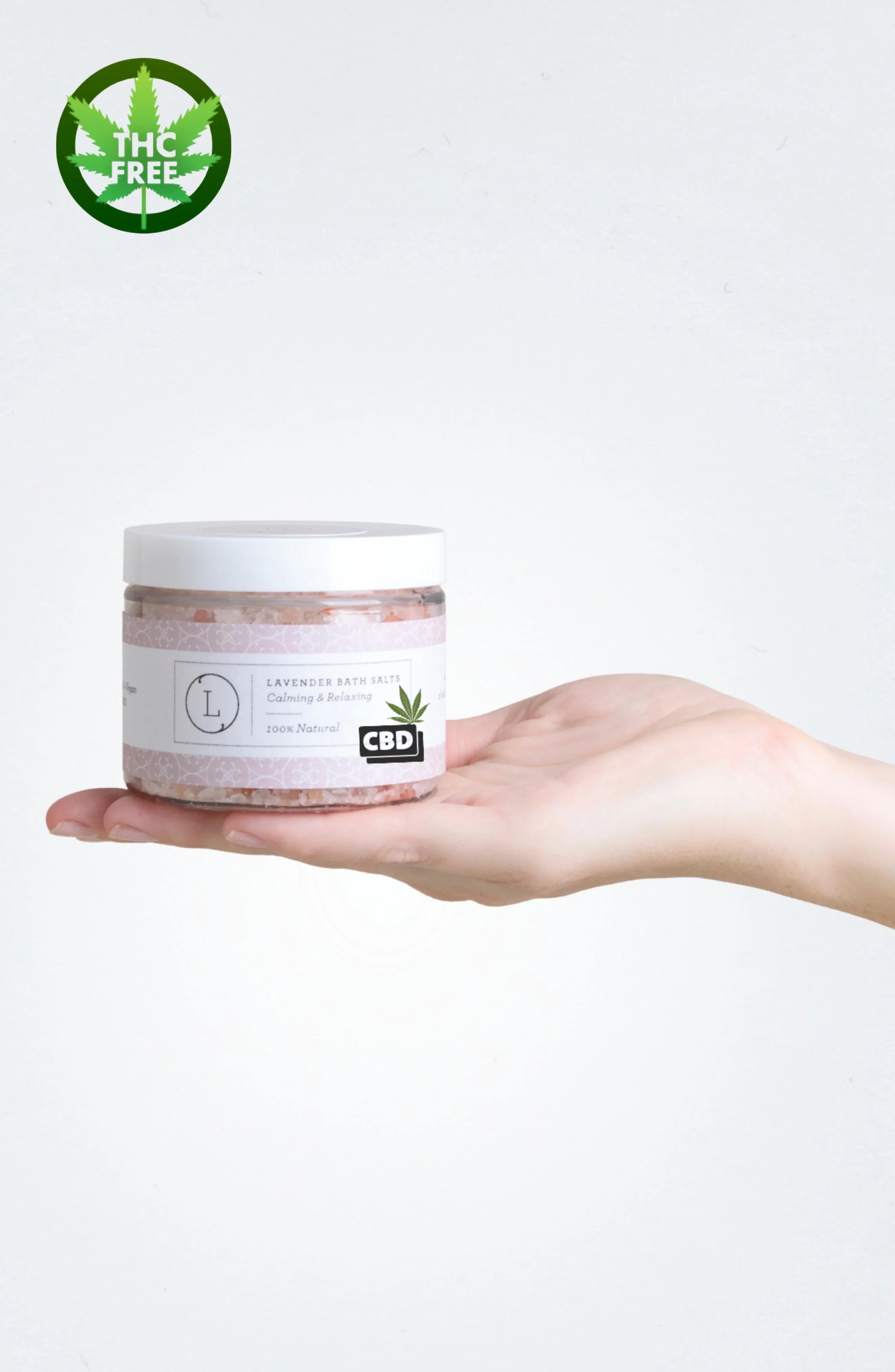 Hand holding jar of lavender CBD bath salts labeled THC free, calming and relaxing