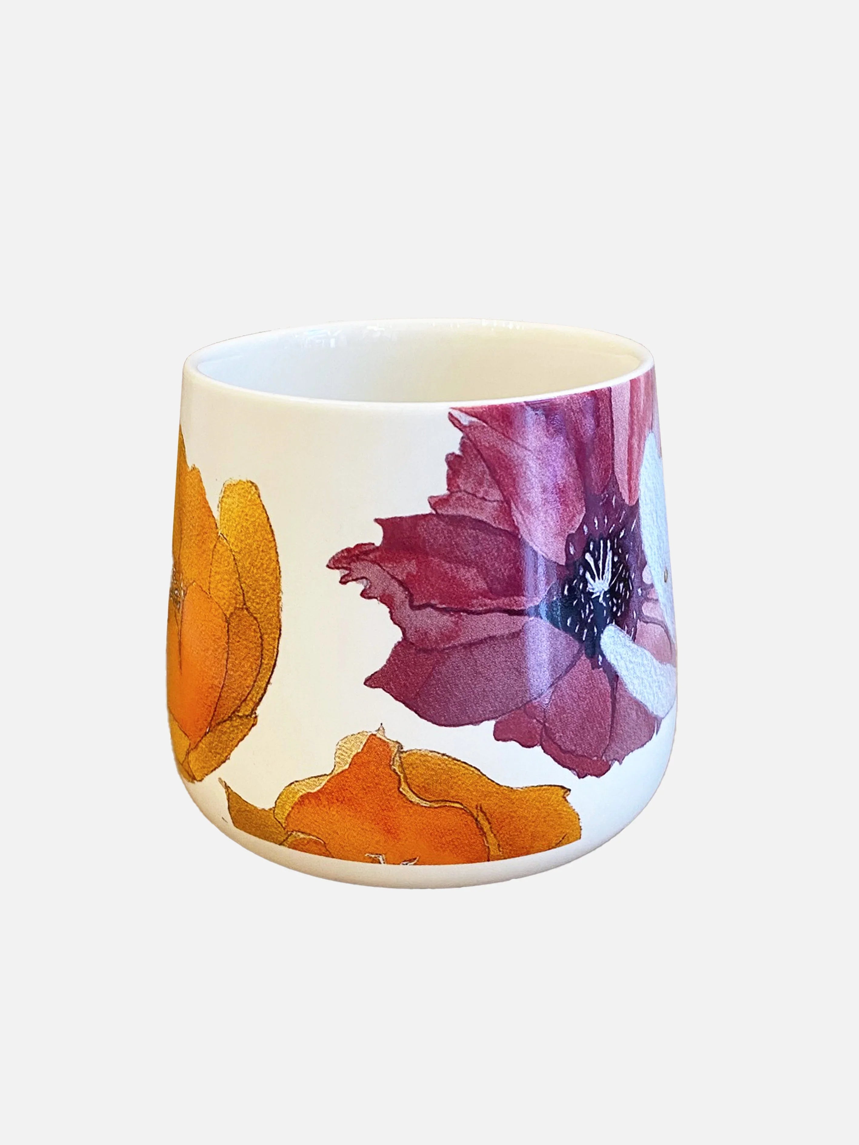 White ceramic mug with large purple and orange floral design, isolated on white background