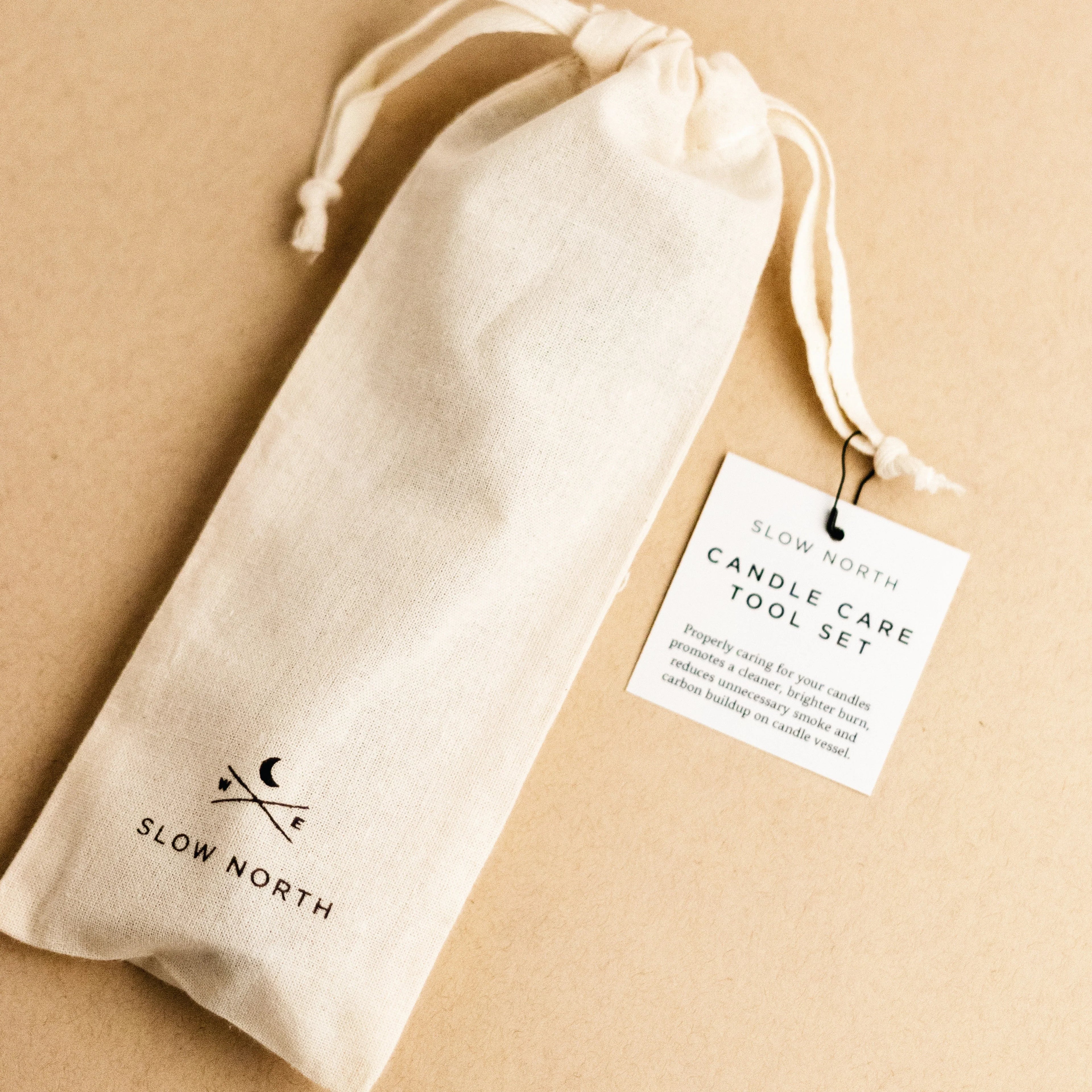 Slow North candle care tool set in a white drawstring pouch with a product tag on beige background