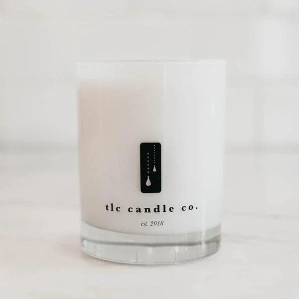 White glass candle by tlc candle co. on marble surface at Qu!rk Boutique, modern and minimalist.