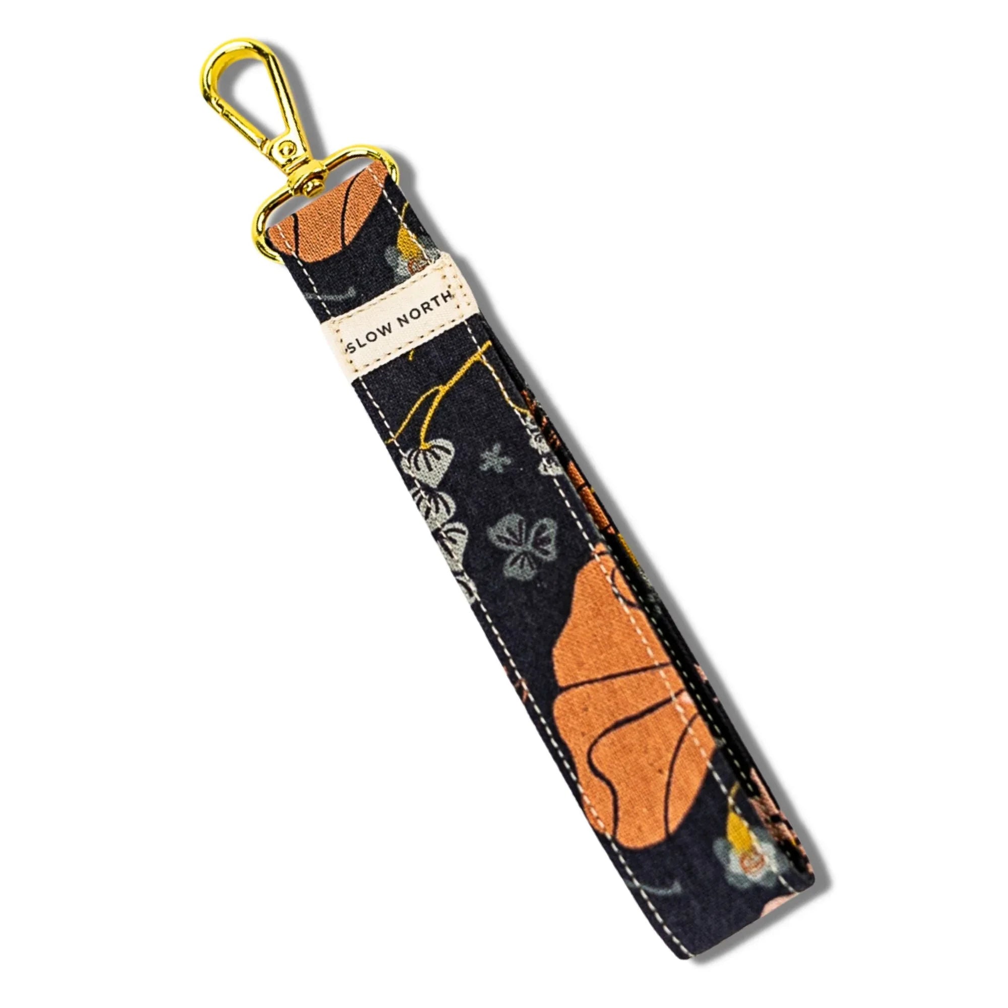Floral fabric wristlet keychain with gold clasp and Slow North label on white background