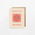 Beige congratulatory card with red sunburst design and text Cheers to You! You Did It!