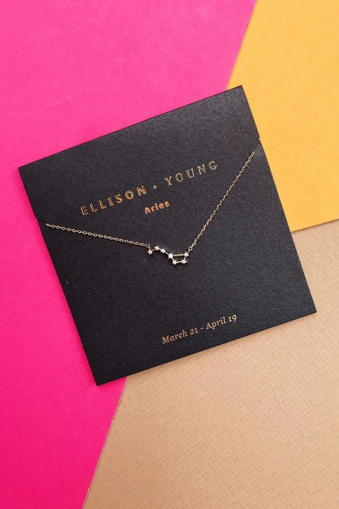 Ellison + Young gold Aries zodiac constellation necklace on black card with pink, yellow, and beige background