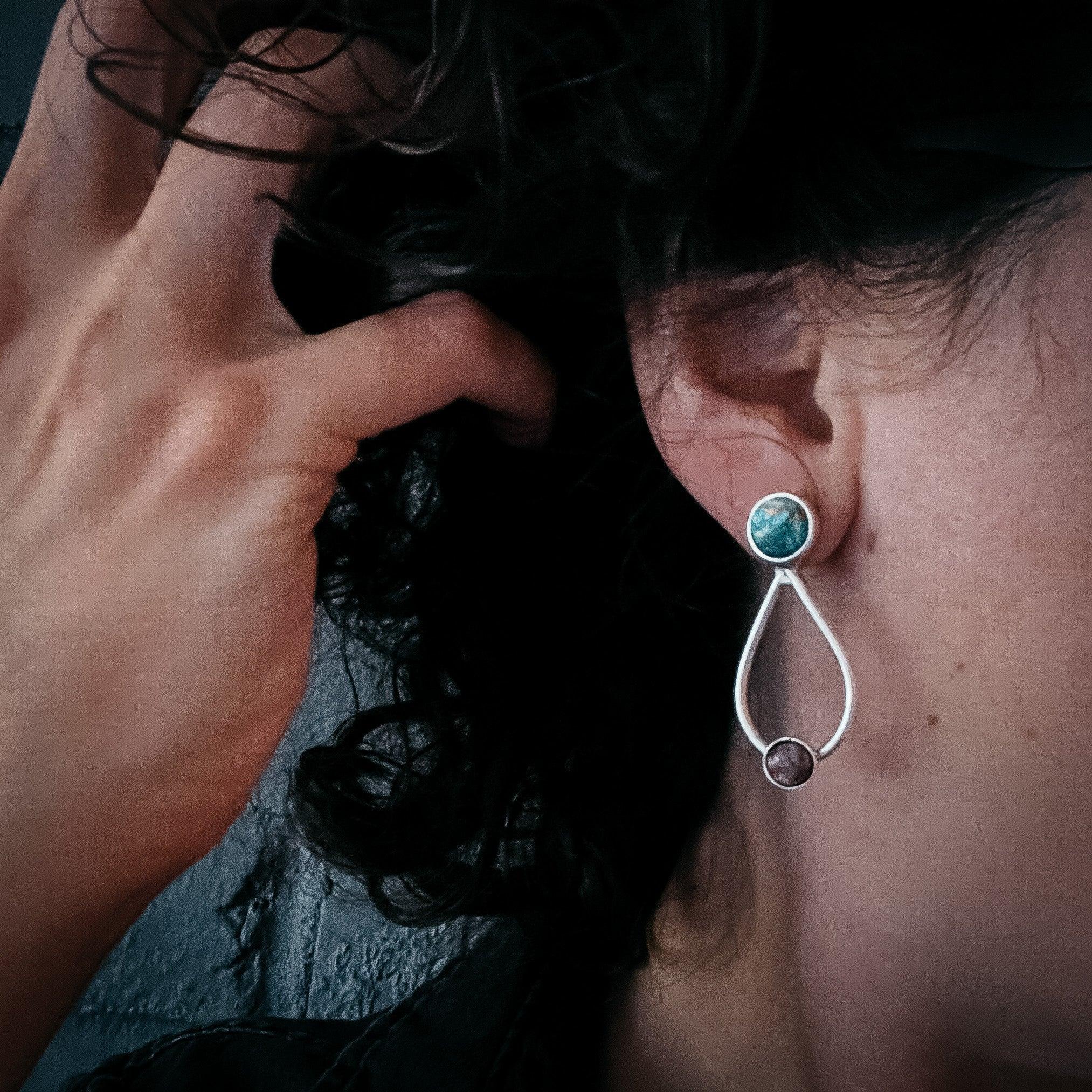 Woman wearing artist-designed silver drop earring with turquoise and brown stones