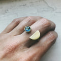 Hand wearing modern artist-designed gold adjustable ring with blue cosmic stone from Qu!rk Boutique