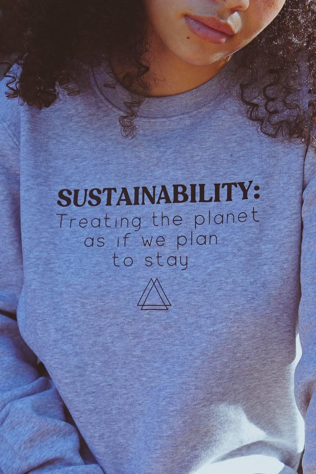 Close-up of person wearing grey sweatshirt with sustainability quote about treating the planet