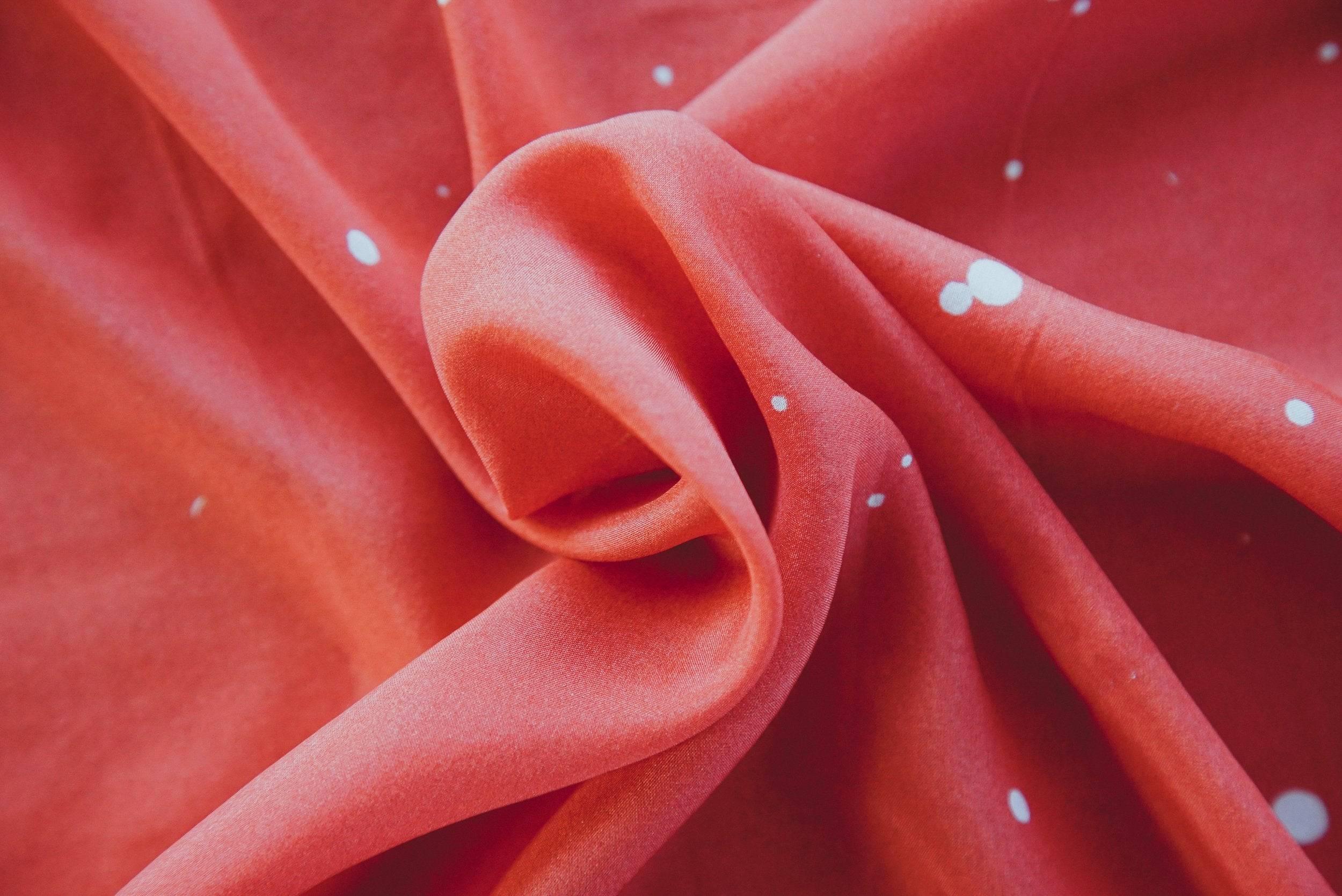 Close-up of red fabric with white polka dots twisted to show texture and softness
