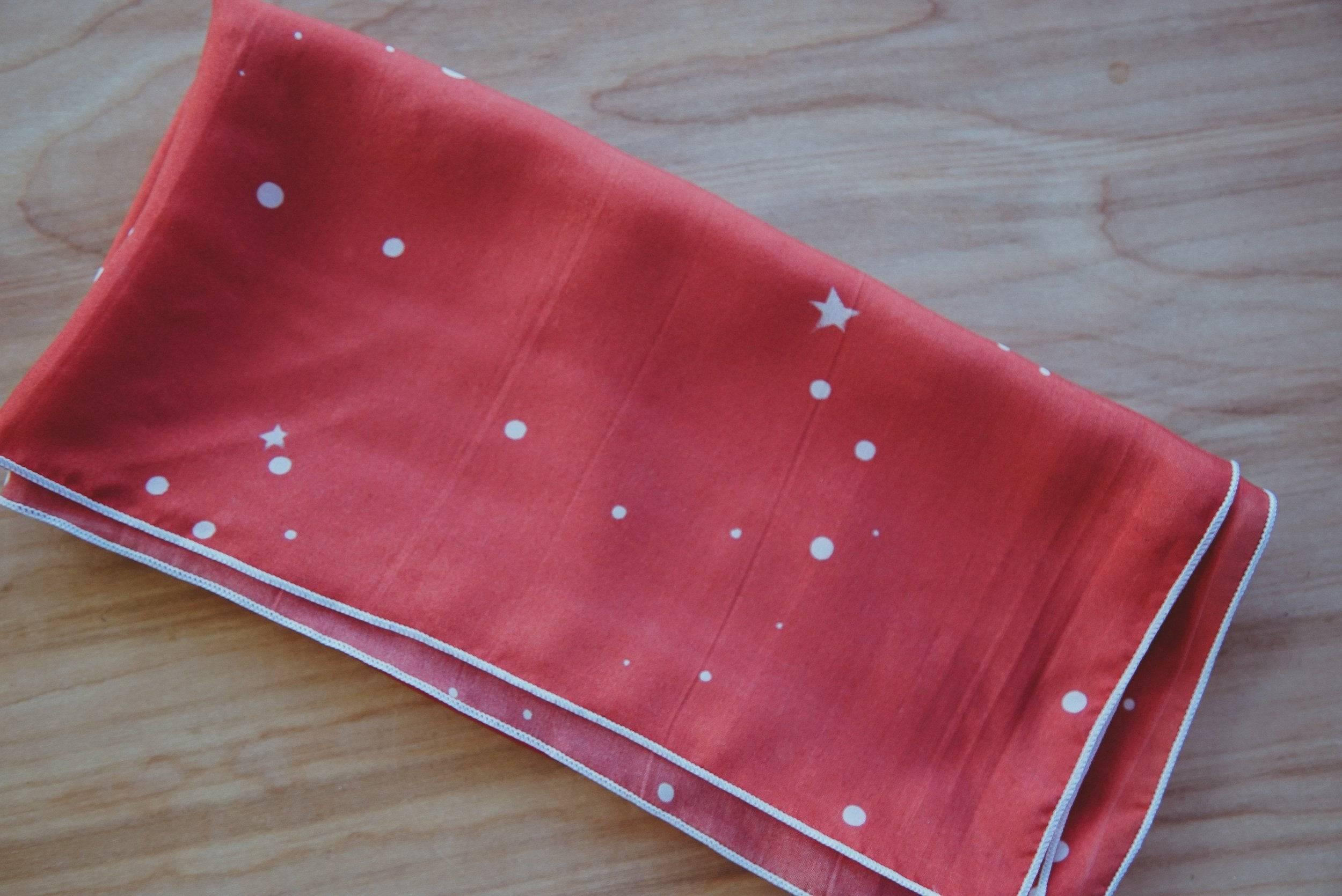 Red folded fabric with white star and dot pattern on a wooden surface