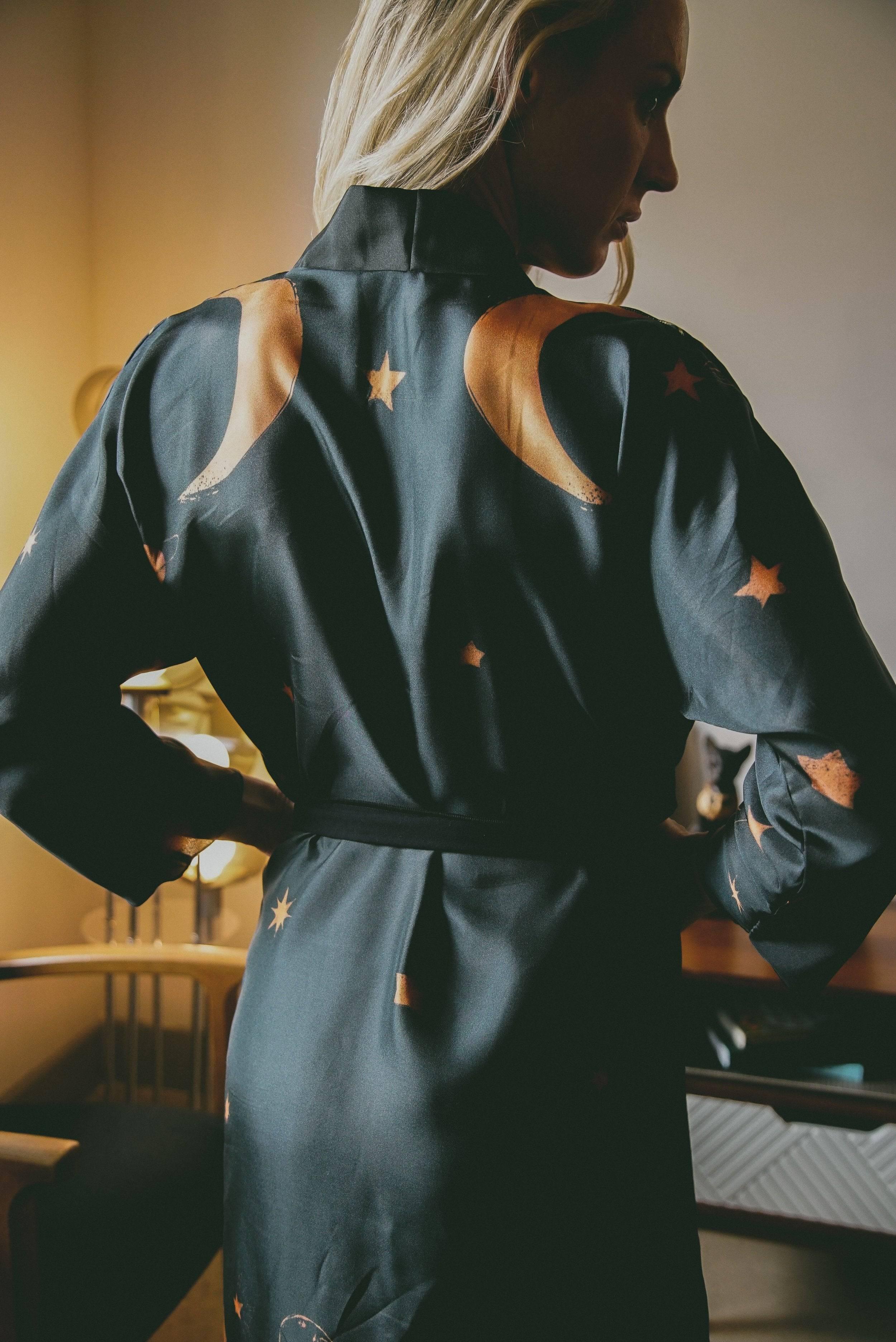 Woman wearing black robe with orange moon and star patterns in cozy indoor setting