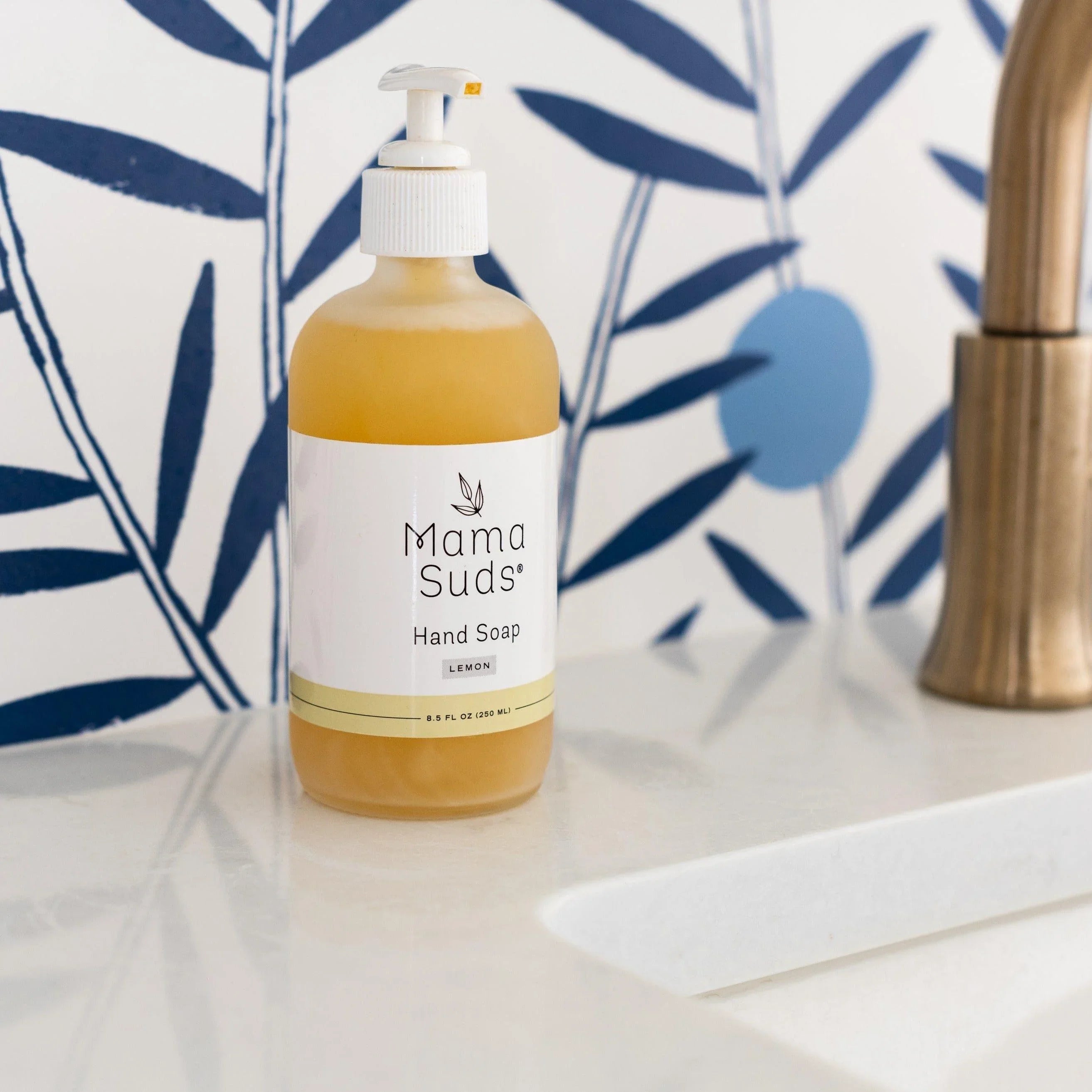Mama Suds lemon hand soap on white sink with modern blue botanical wallpaper, Qu!rk Boutique