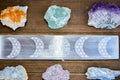 Selenite crystal engraved with tree of life and moon phases, surrounded by colorful healing crystals
