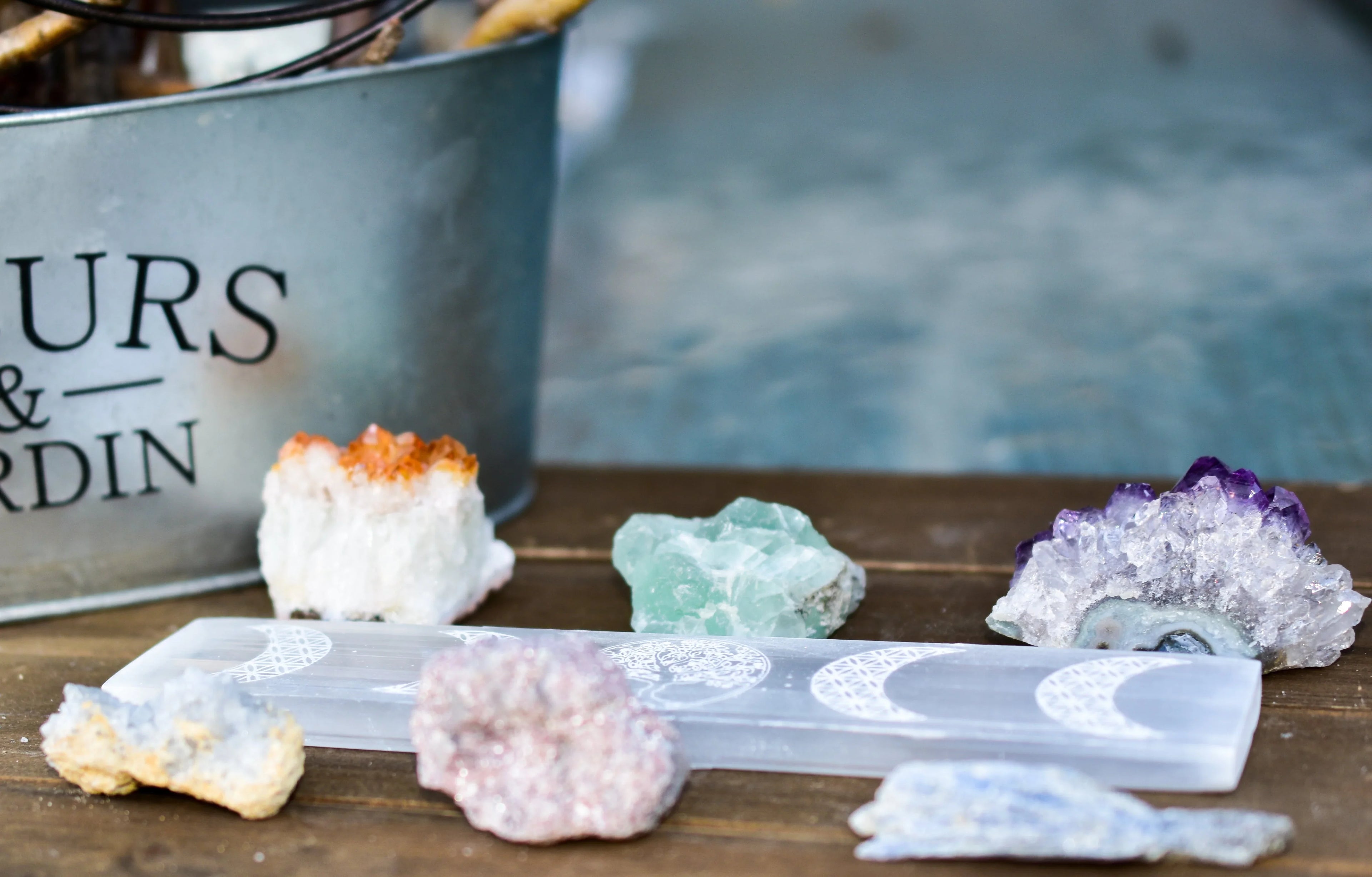 assorted colorful healing crystals and a selenite moon phase wand on wooden surface