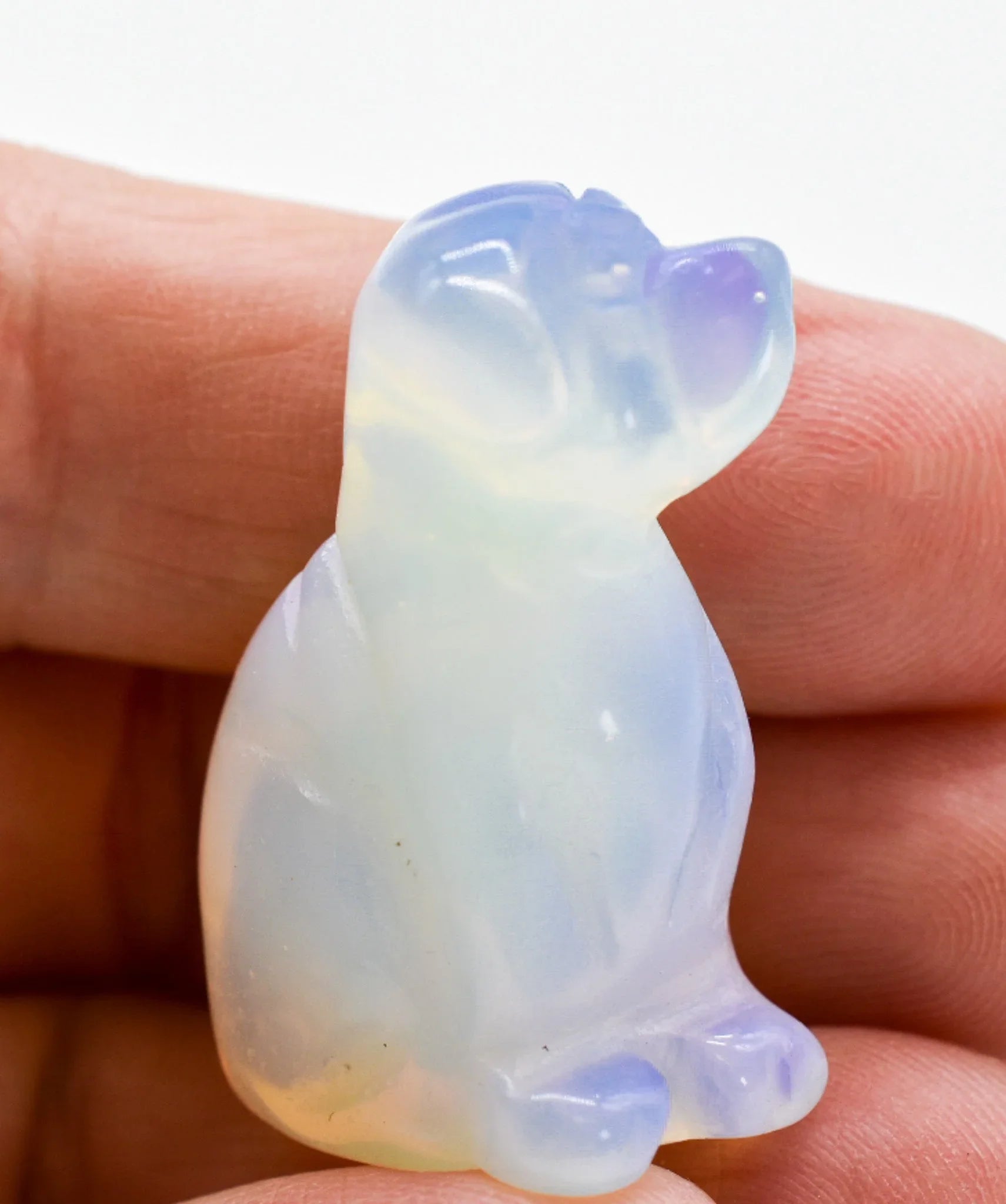 Hand holding a small opalite dog figurine, gemstone gift from Qu!rk Boutique