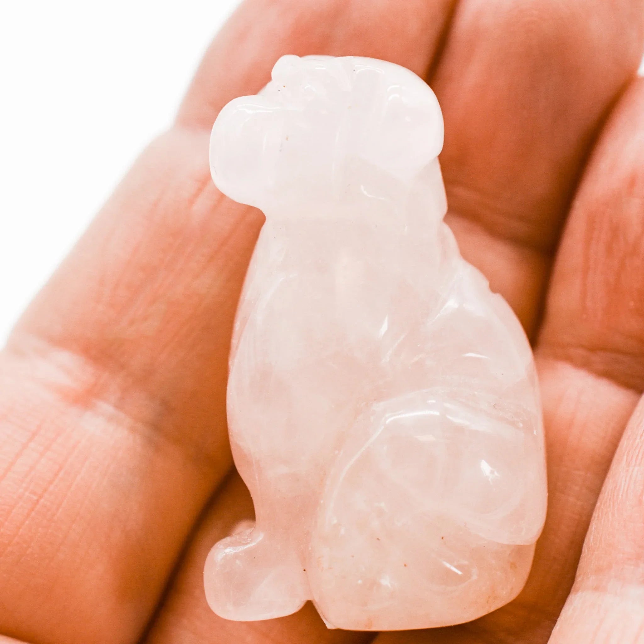 Hand holding a small rose quartz monkey figurine from Qu!rk Boutique