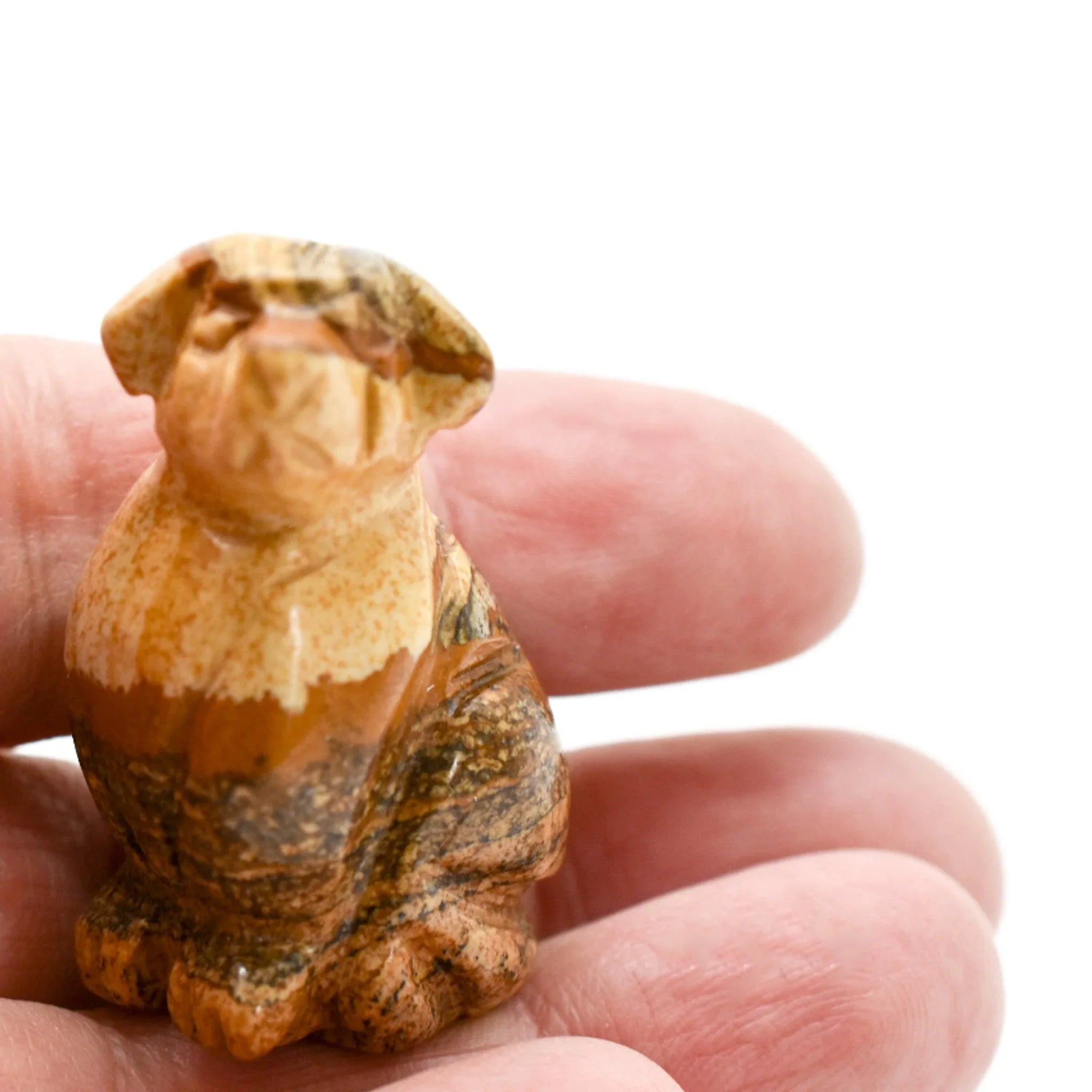 Hand holding a small carved stone dog figurine, artisan gift from Qu!rk Boutique