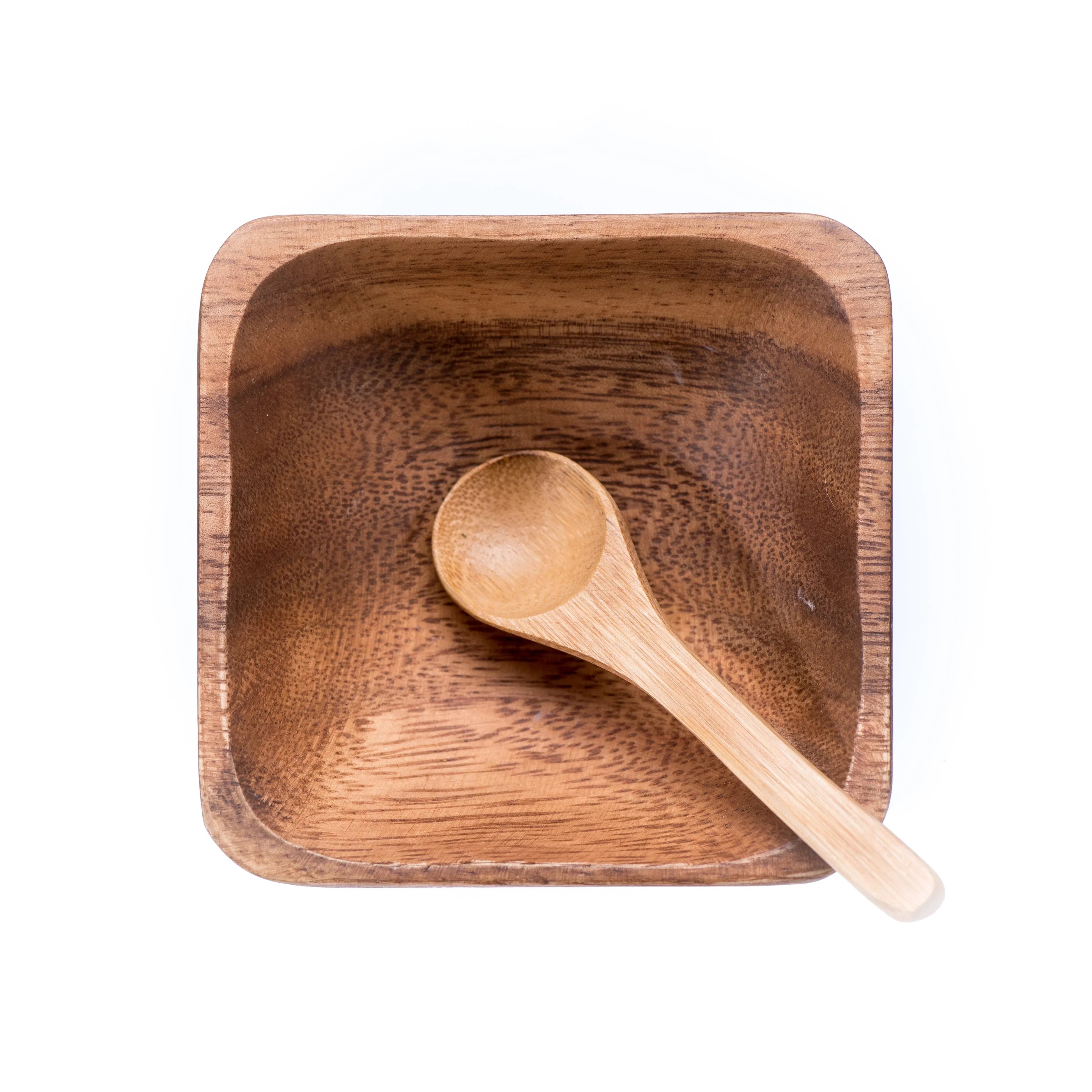 Square wooden bowl with a small wooden spoon on white background