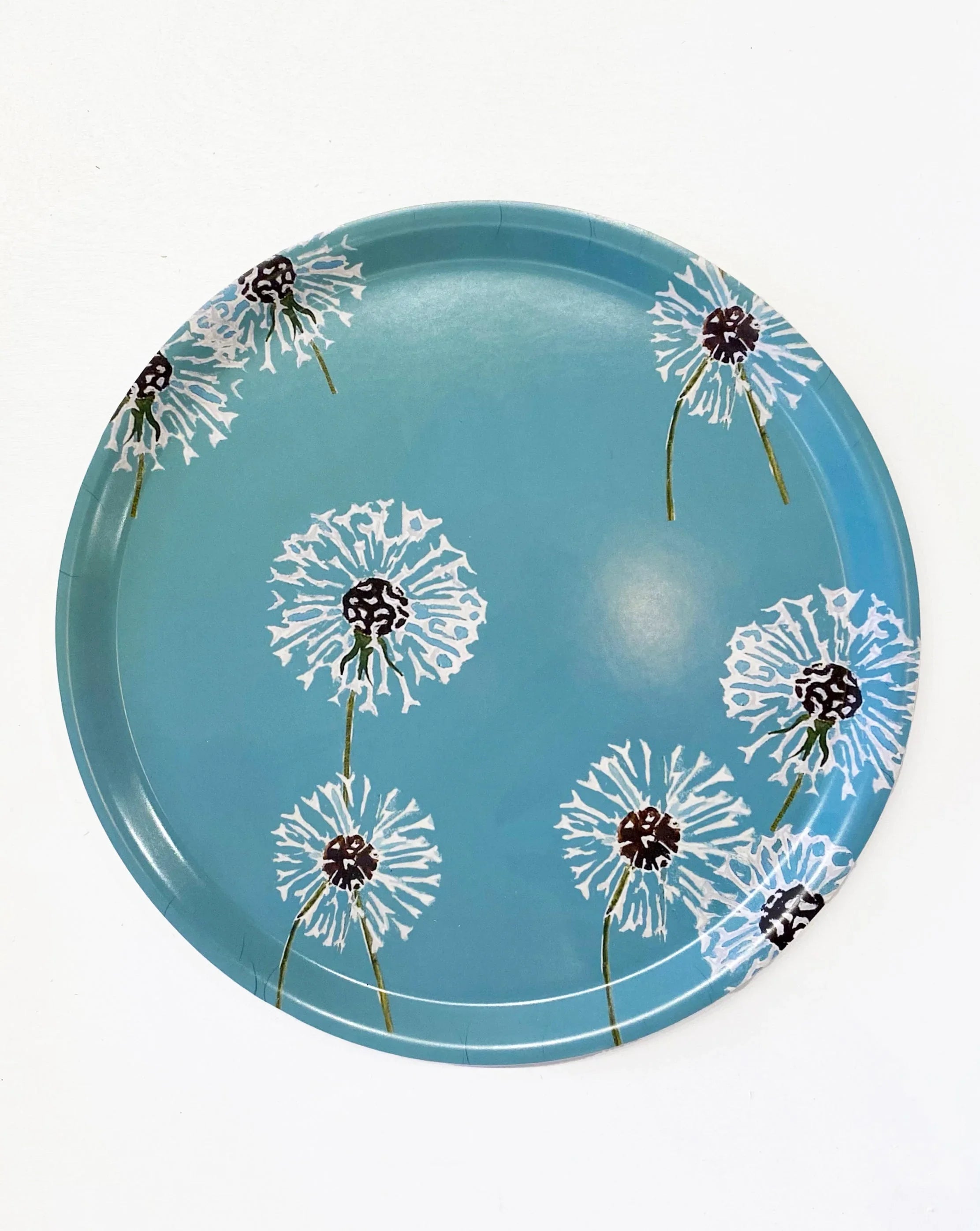 Round blue serving tray with white dandelion floral design on a white background