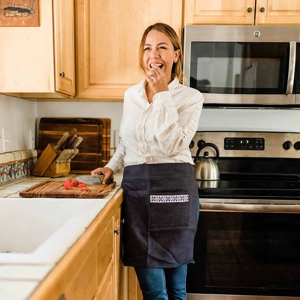 Smiling woman in artisan apron preparing strawberries in a bright kitchen at Qu!rk Boutique