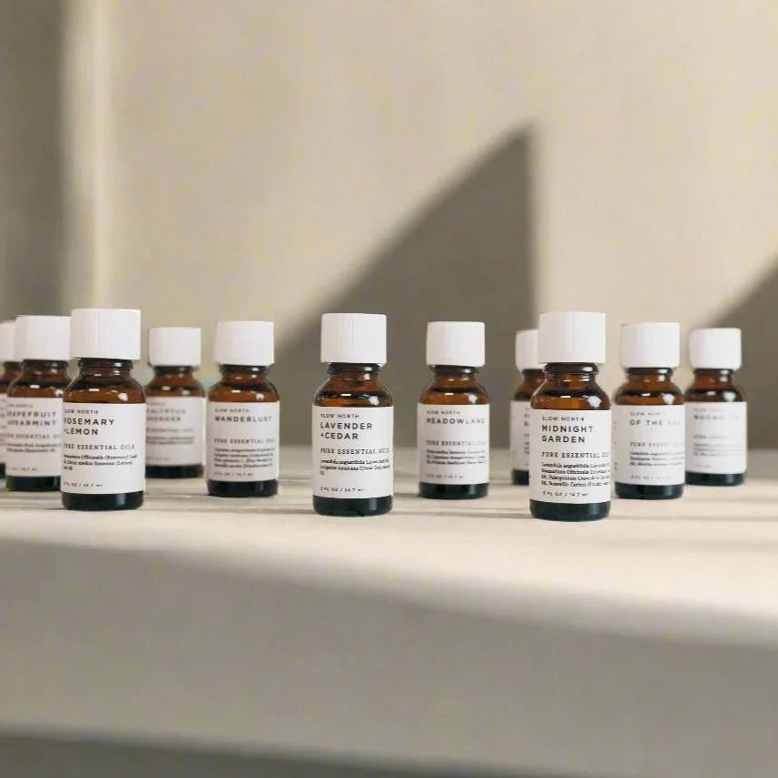 Essential oil diffuser blends in amber glass bottles with white caps on a neutral surface at Qu!rk Boutique.