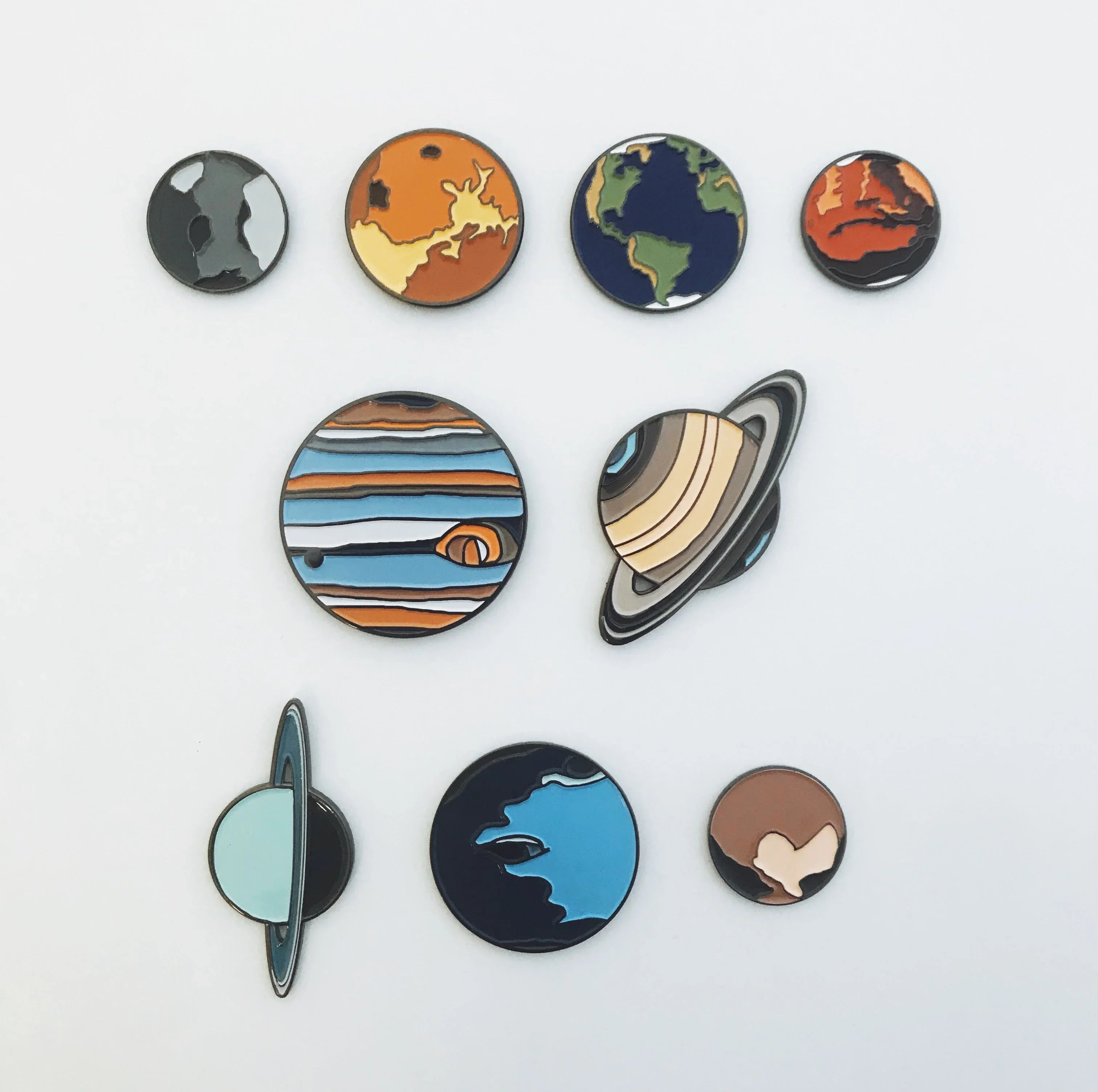 Colorful enamel pins of nine planets and moons on white background, space-themed collection