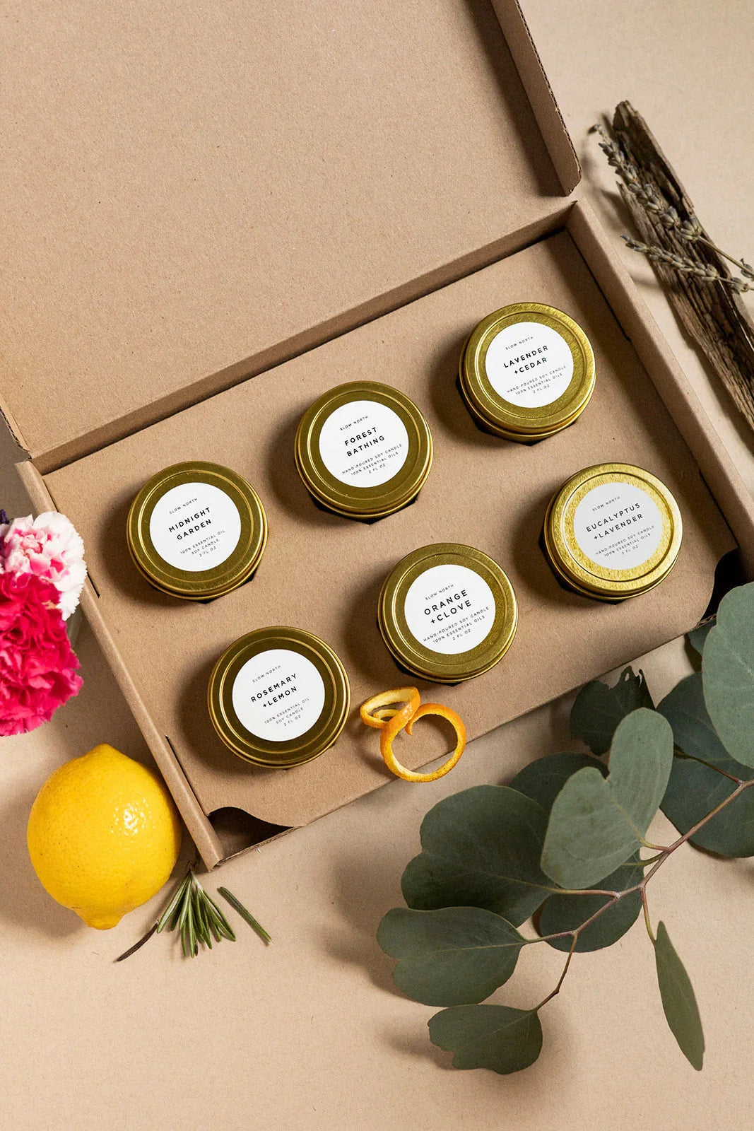 Gift box with six gold tins of soy candles in scents like lavender cedar, eucalyptus, and rosemary lemon