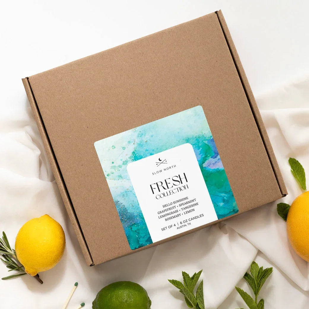 Slow North Fresh Collection candle gift box with citrus and herb scents, surrounded by lemons, lime, and mint