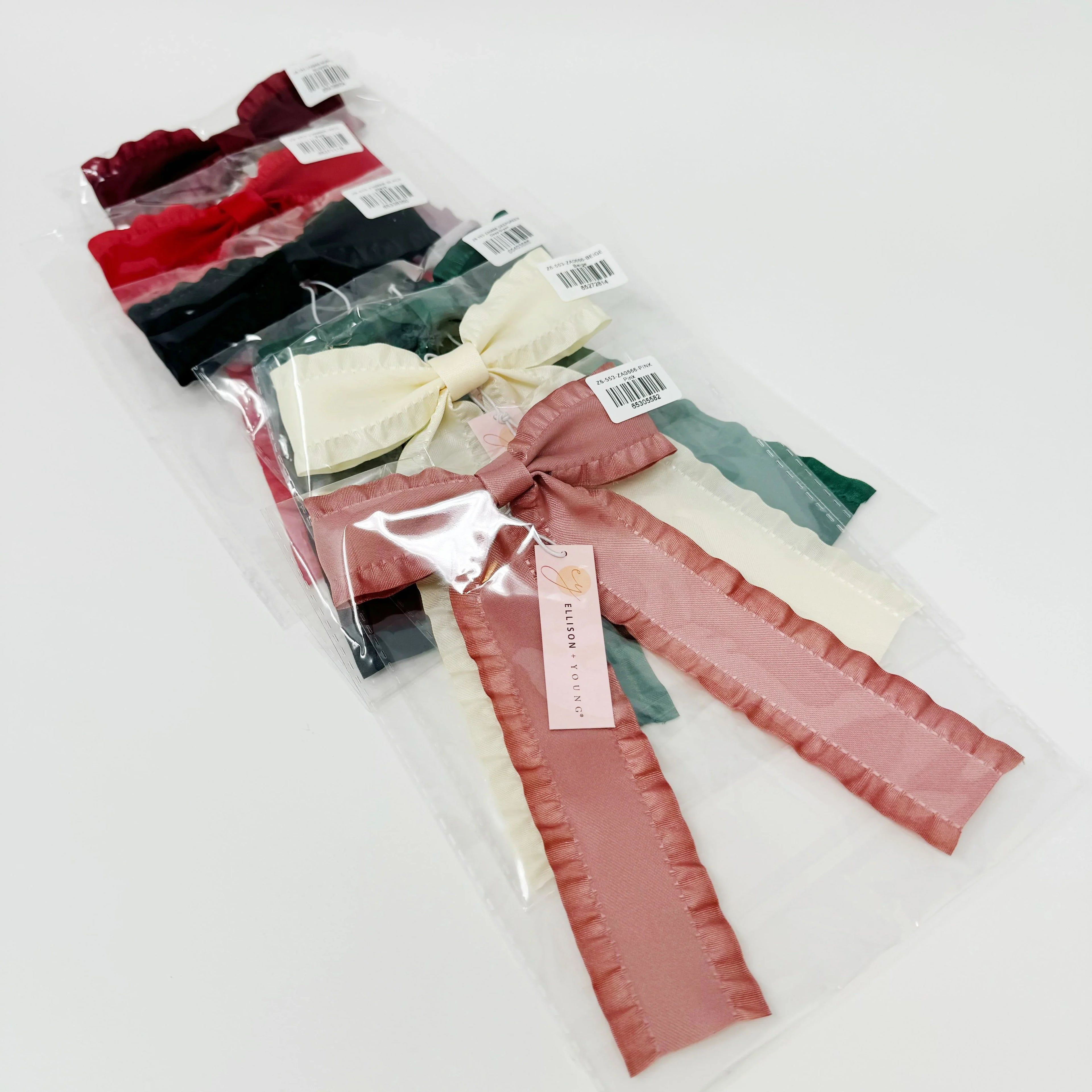 Set of colorful fabric bow hair accessories with tags, packaged in clear plastic, displayed on white surface