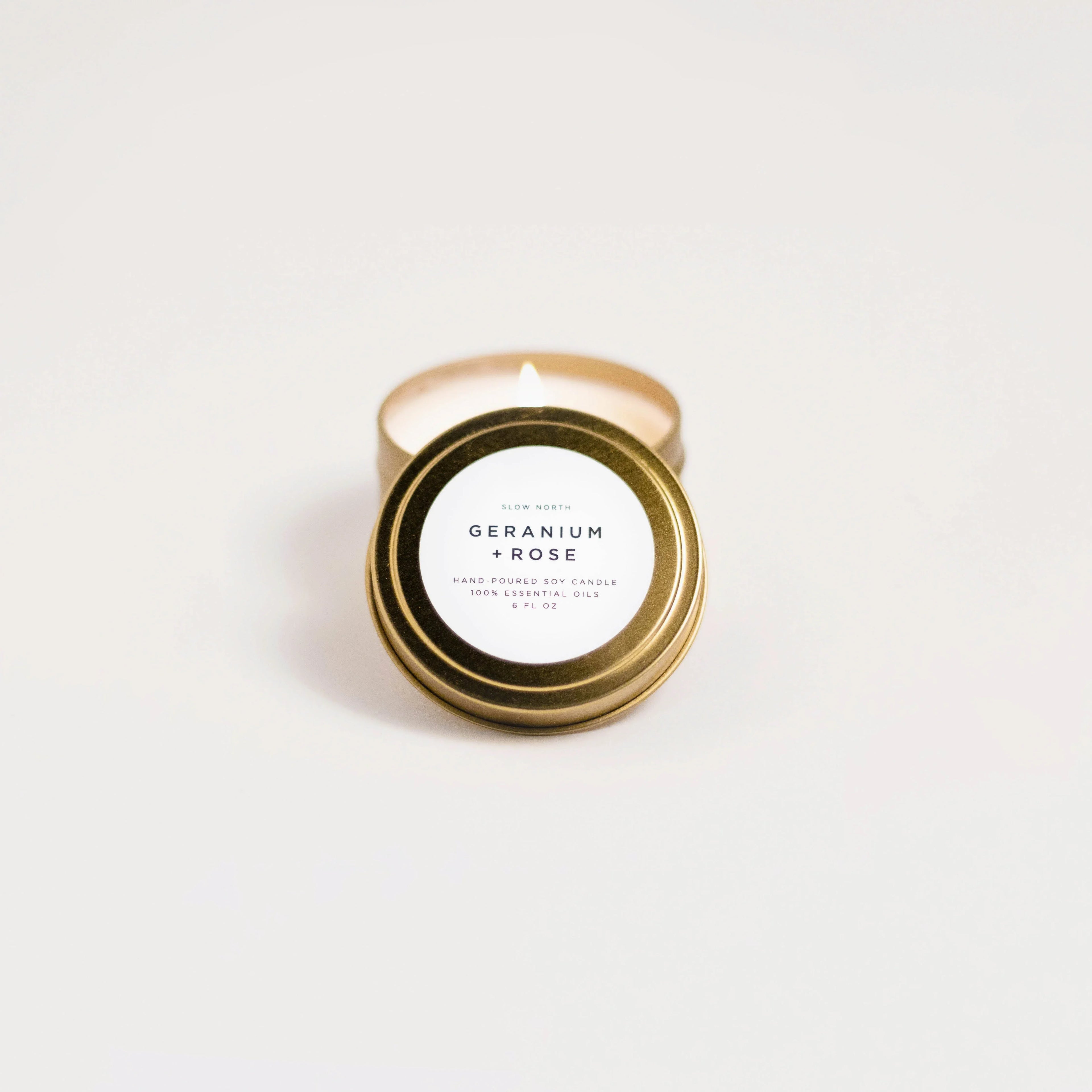 Slow North Geranium Rose travel tin candle with gold lid on white background at Qu!rk Boutique