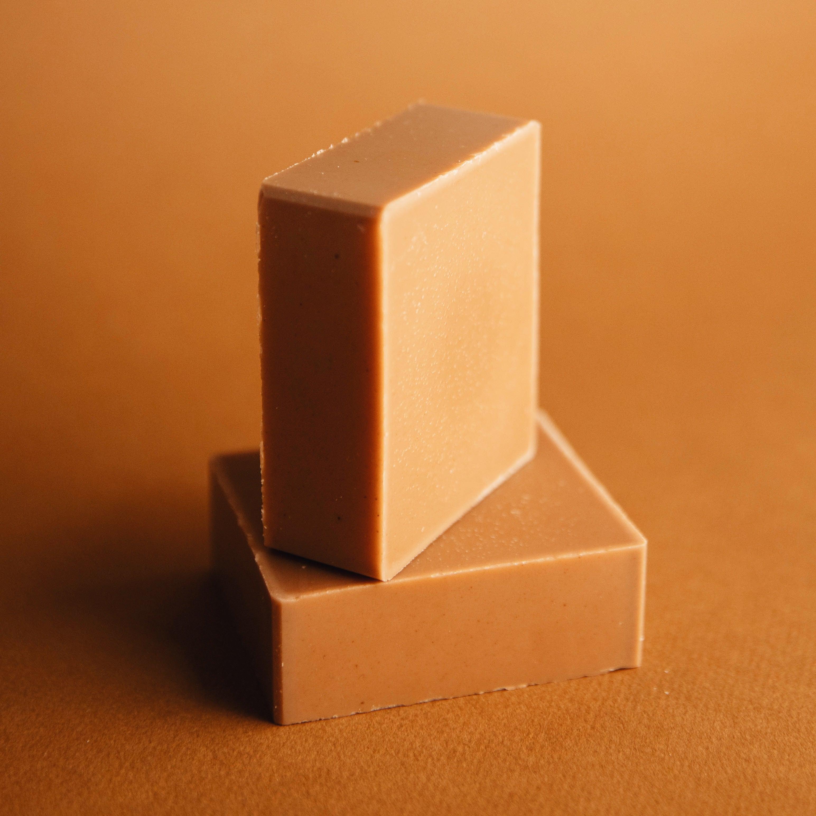 Two rectangular grapefruit spearmint natural soap bars stacked on a brown background