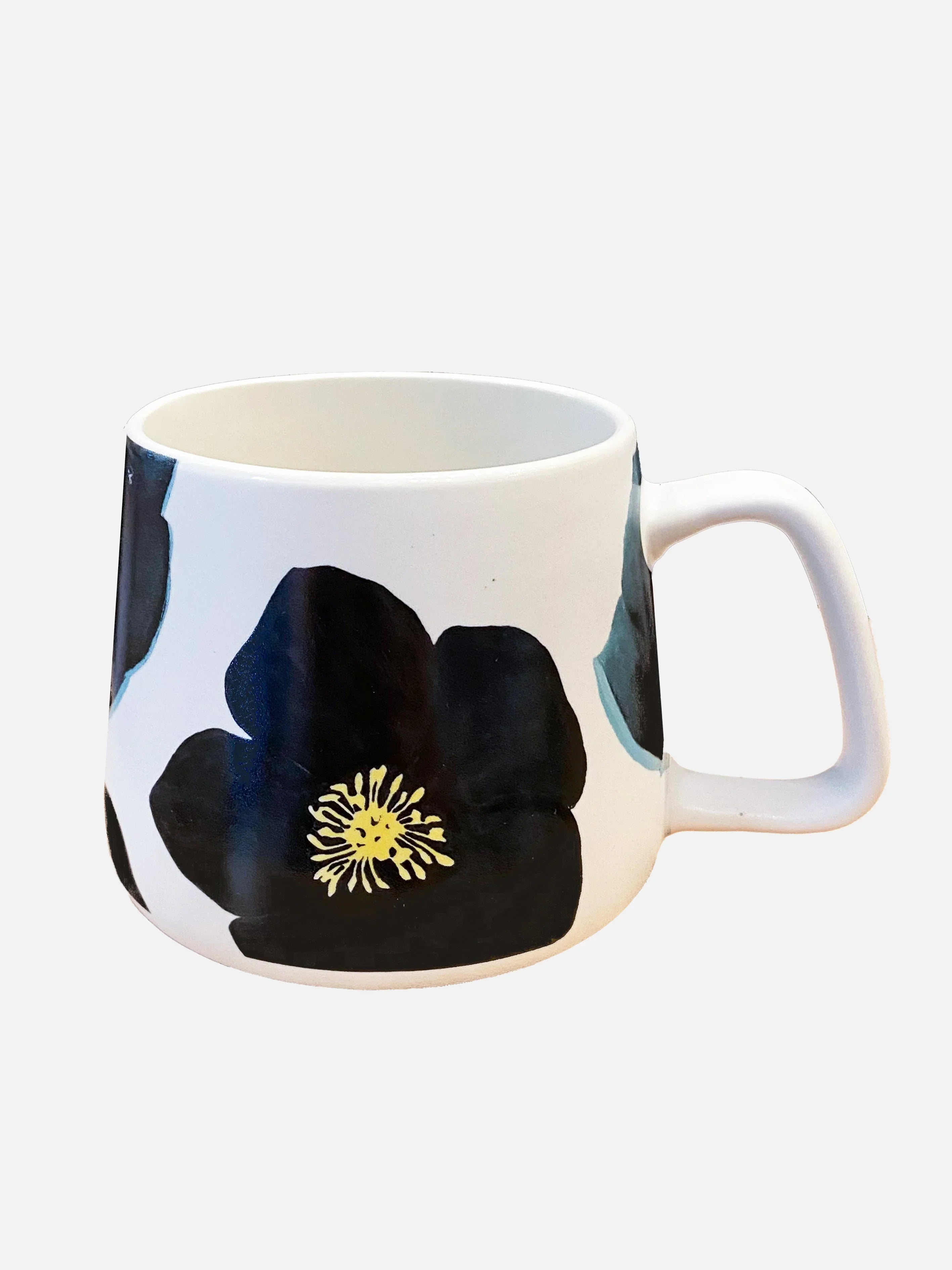 White ceramic mug with large black flower and yellow center design, angled handle, isolated