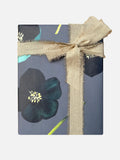 Square gift box wrapped in dark floral paper with large black flowers and beige frayed linen ribbon