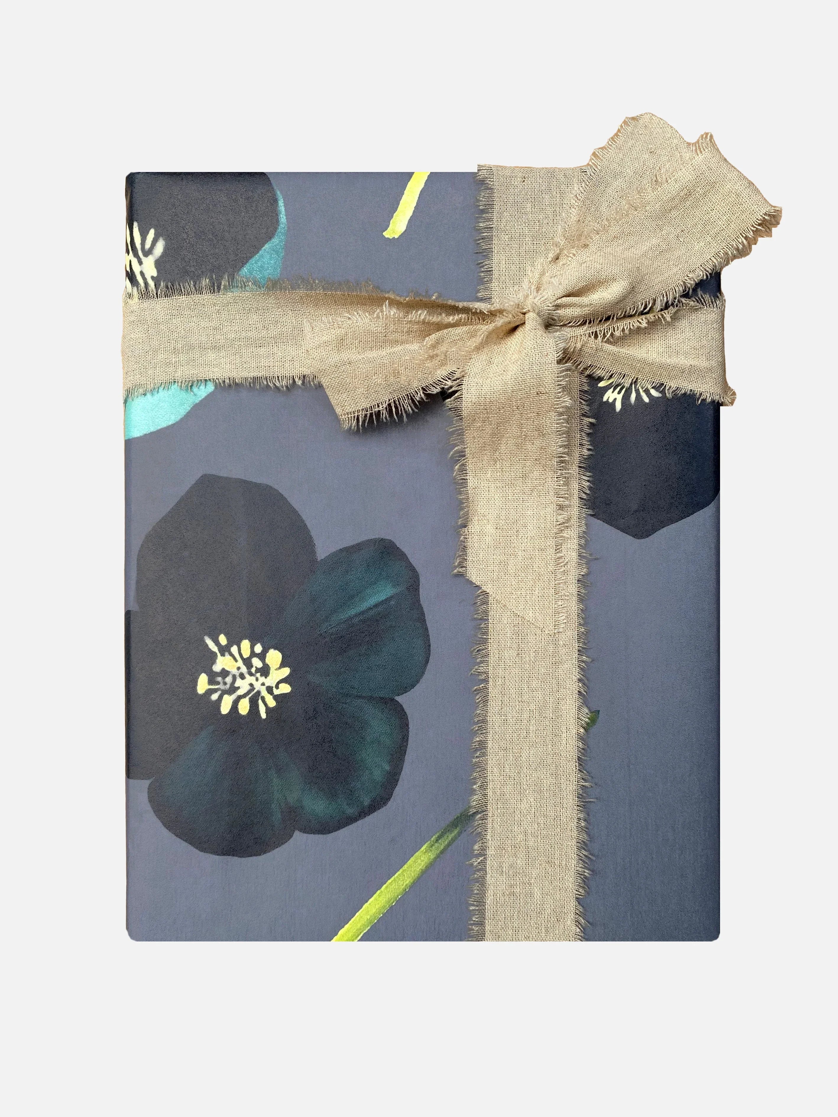 Square gift box wrapped in dark floral paper with large black flowers and beige frayed linen ribbon