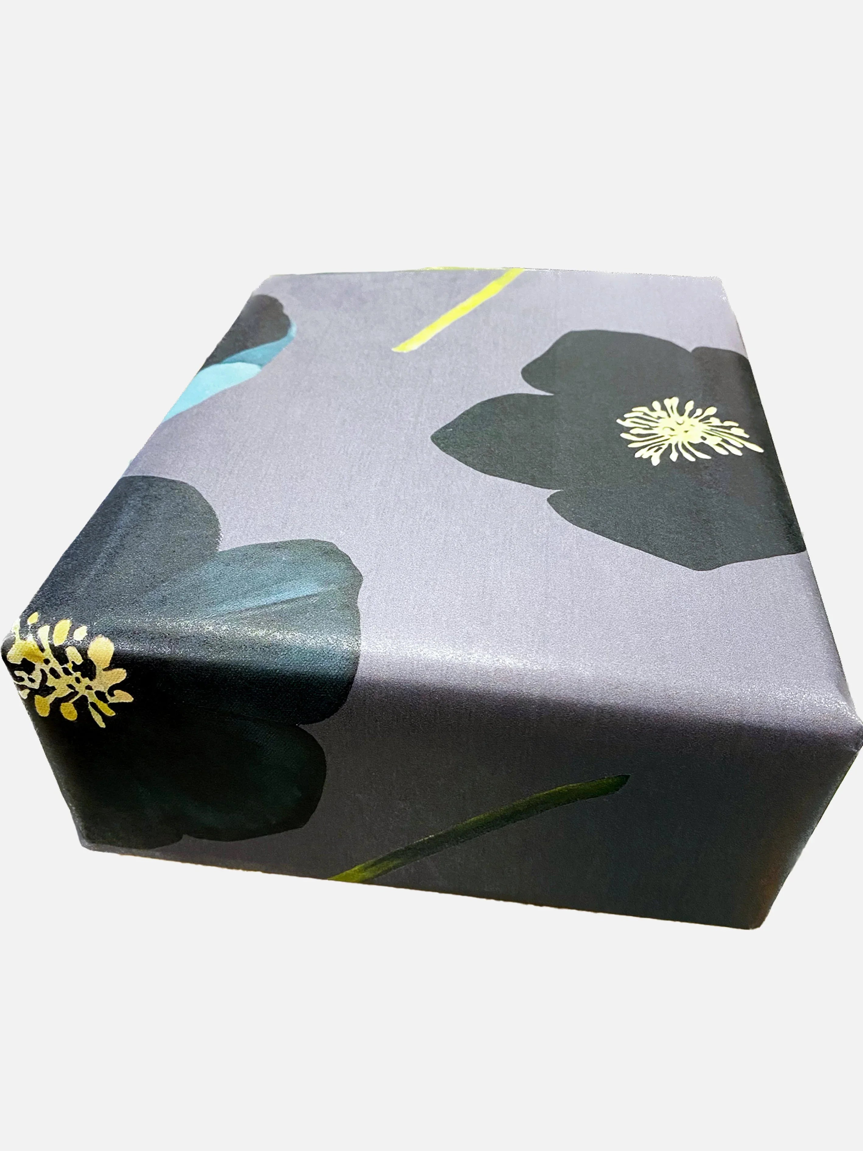 Square gift box wrapped in green winter rose floral wrapping paper with black and yellow flowers