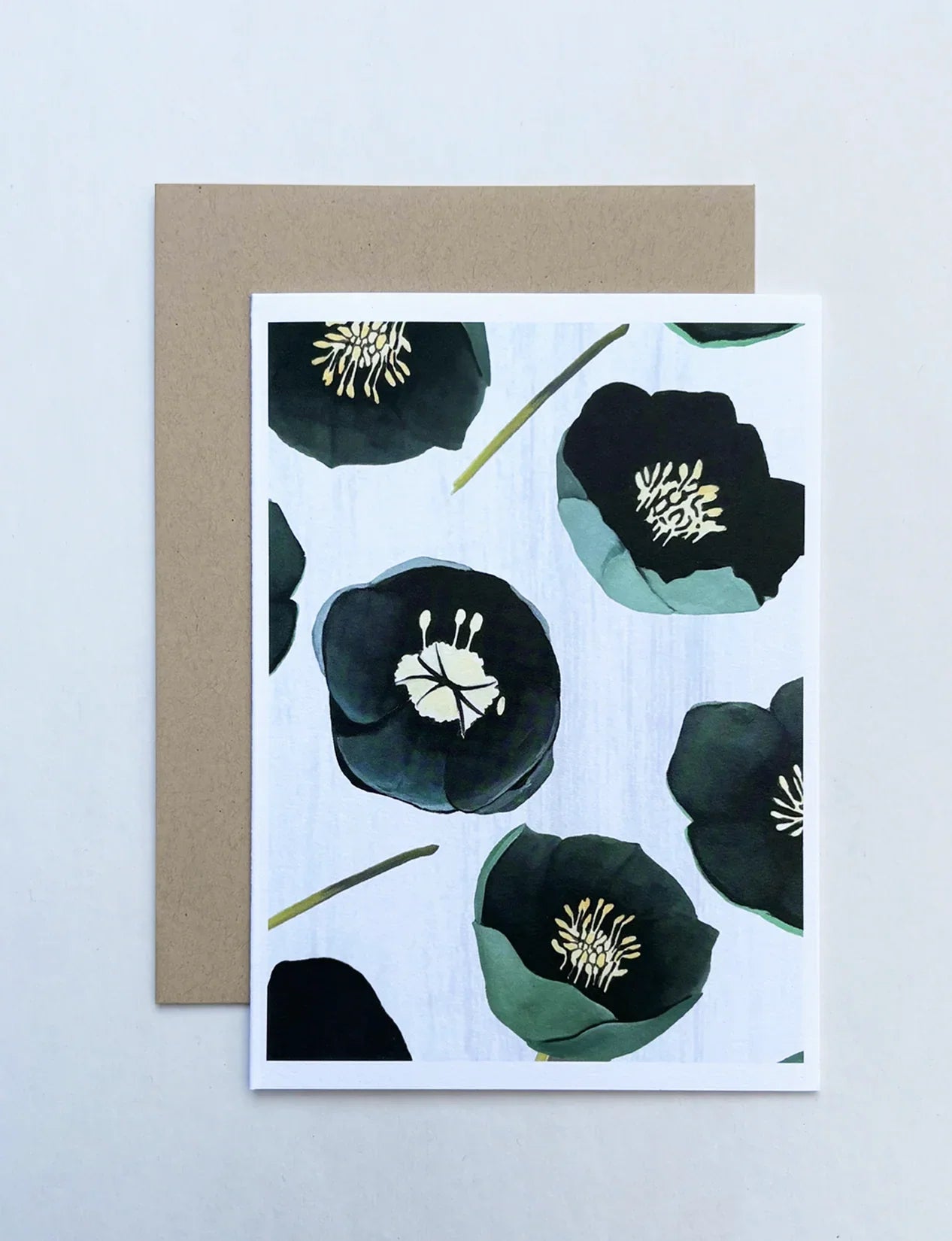 Notecard with green winter rose floral design on light background and brown envelope