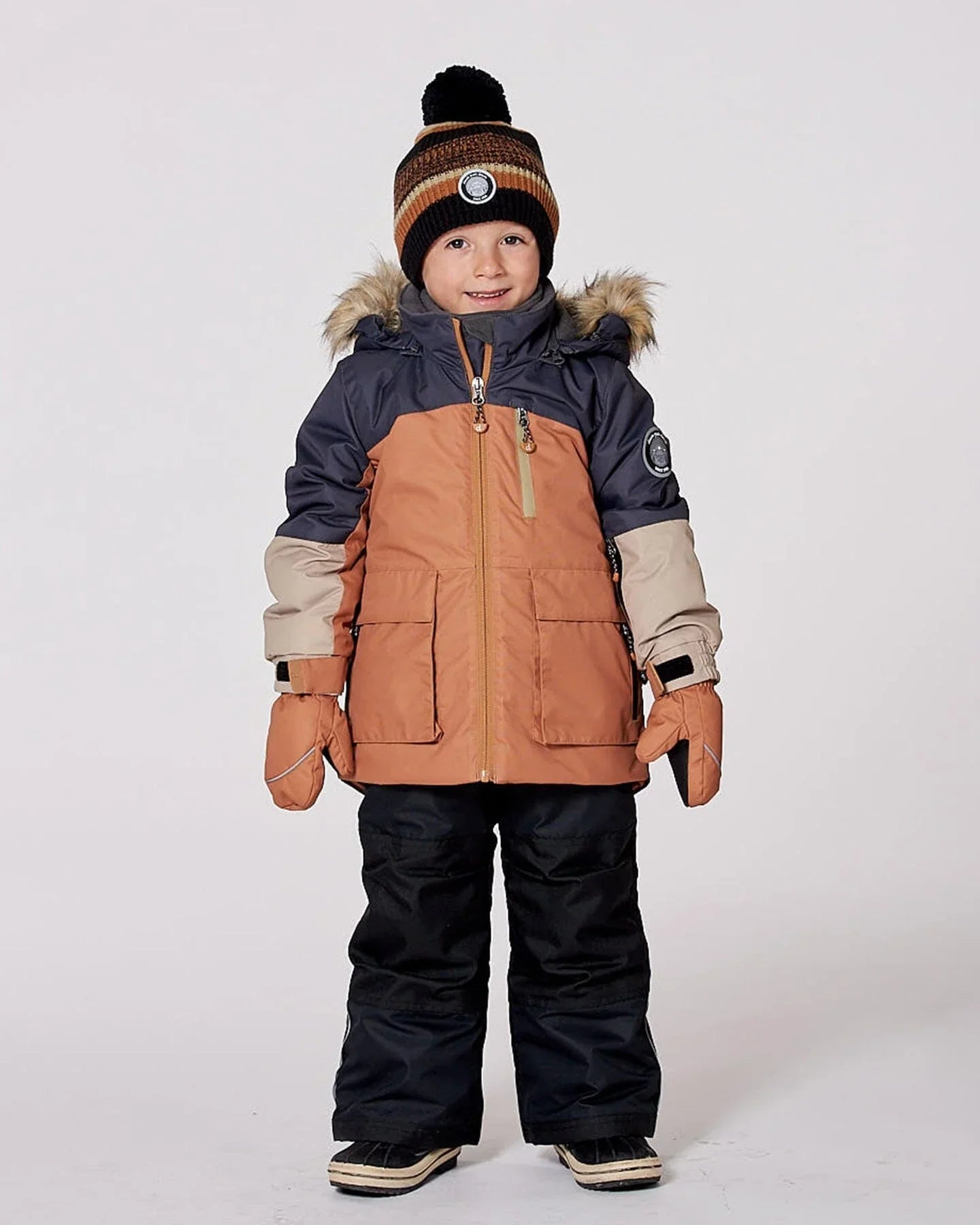 Child in winter coat, beanie, mittens, and snow pants, styled for Qu!rk Boutique gift shop
