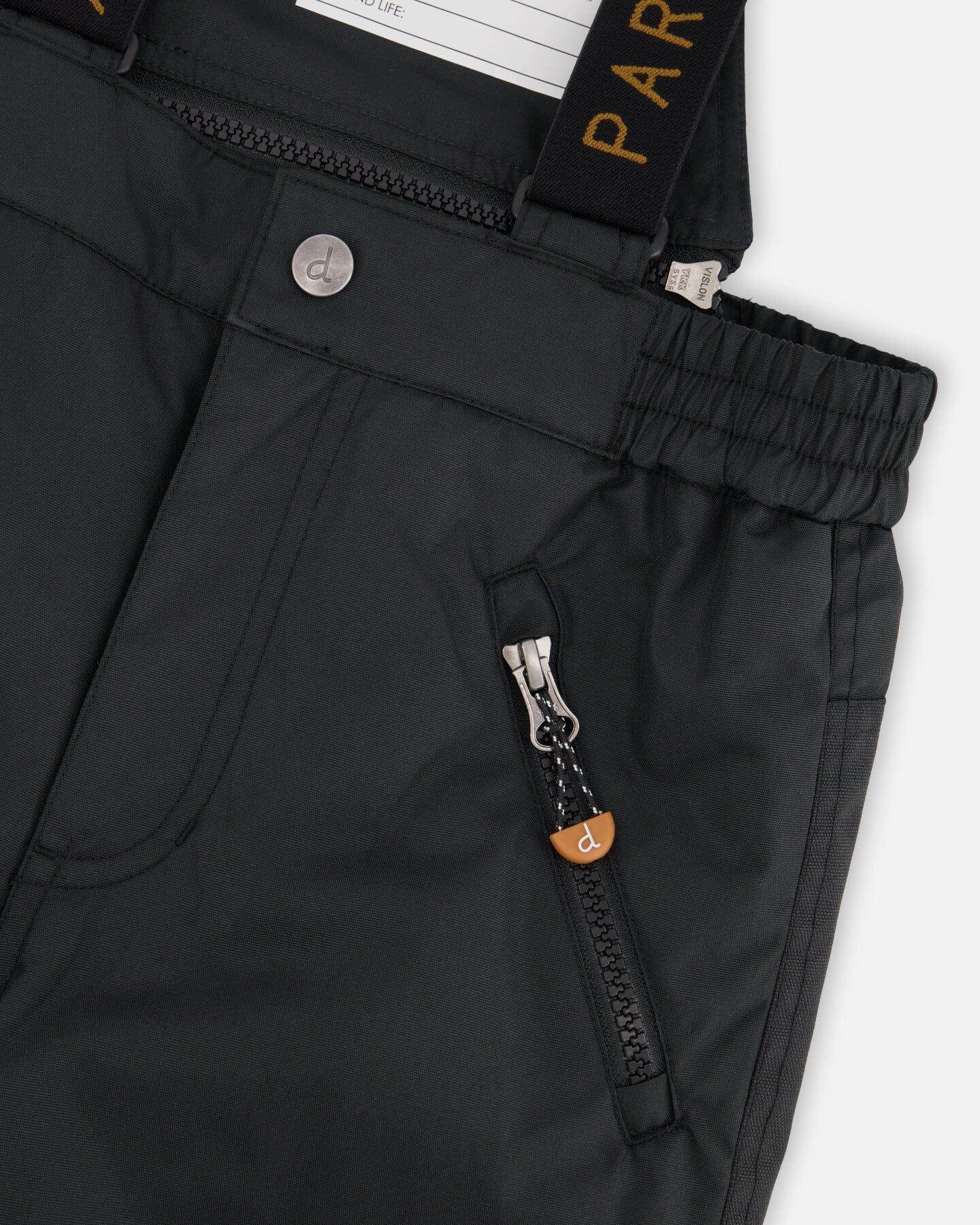 Close-up of black winter pants with zip pocket, button, and adjustable elastic waist at Qu!rk Boutique