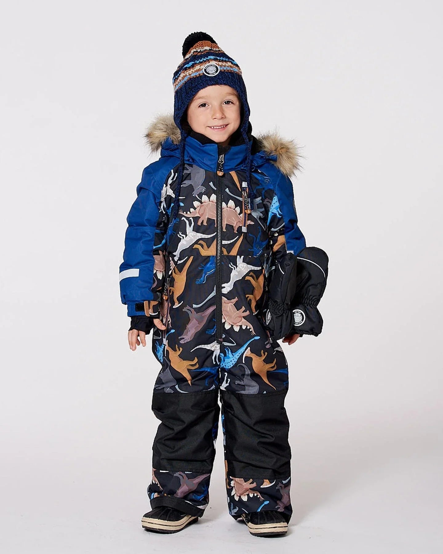 Smiling child in dinosaur-print snowsuit, winter hat, and mittens at Qu!rk Boutique