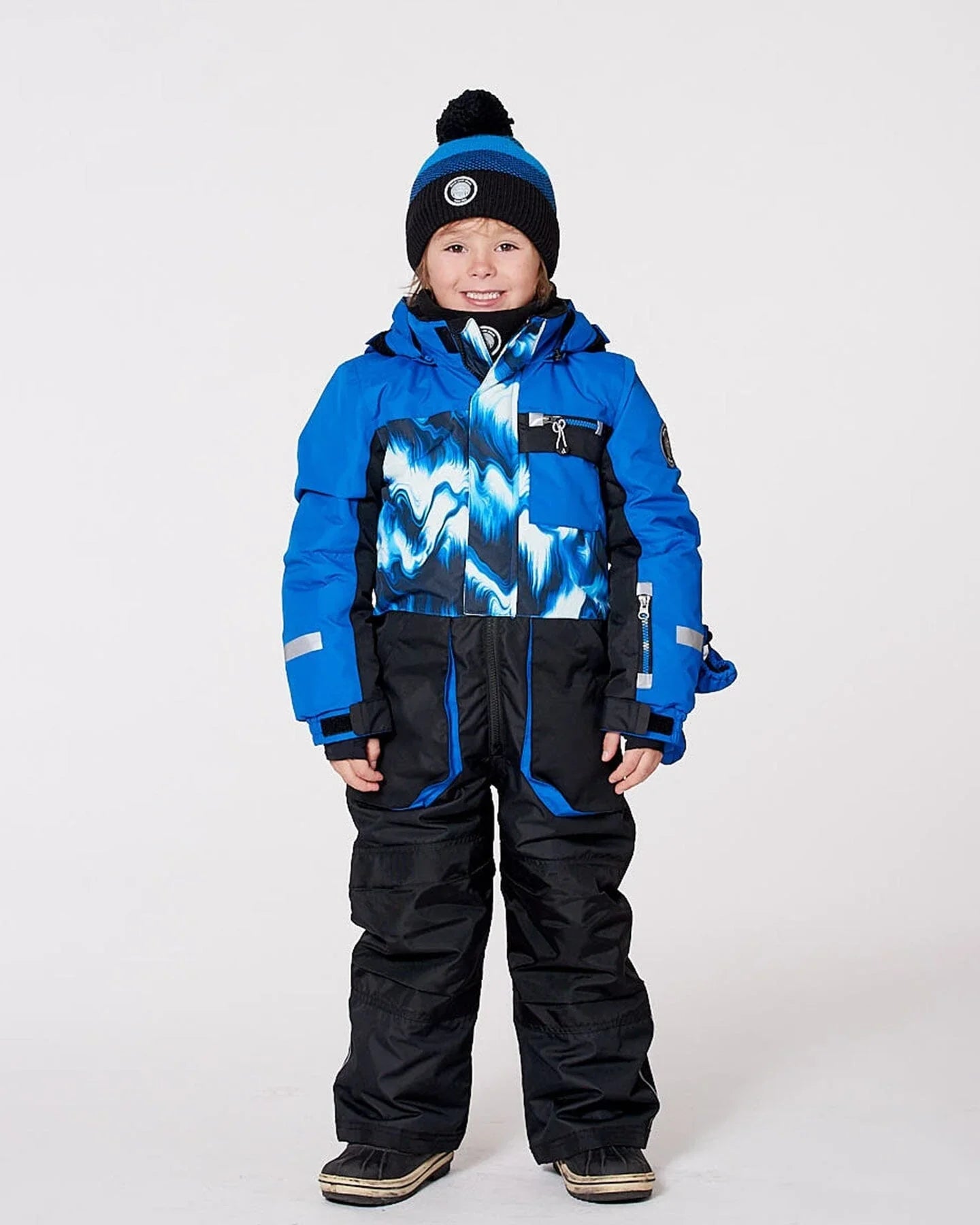 Smiling child in blue and black winter snowsuit and beanie, Qu!rk Boutique winter kidswear.