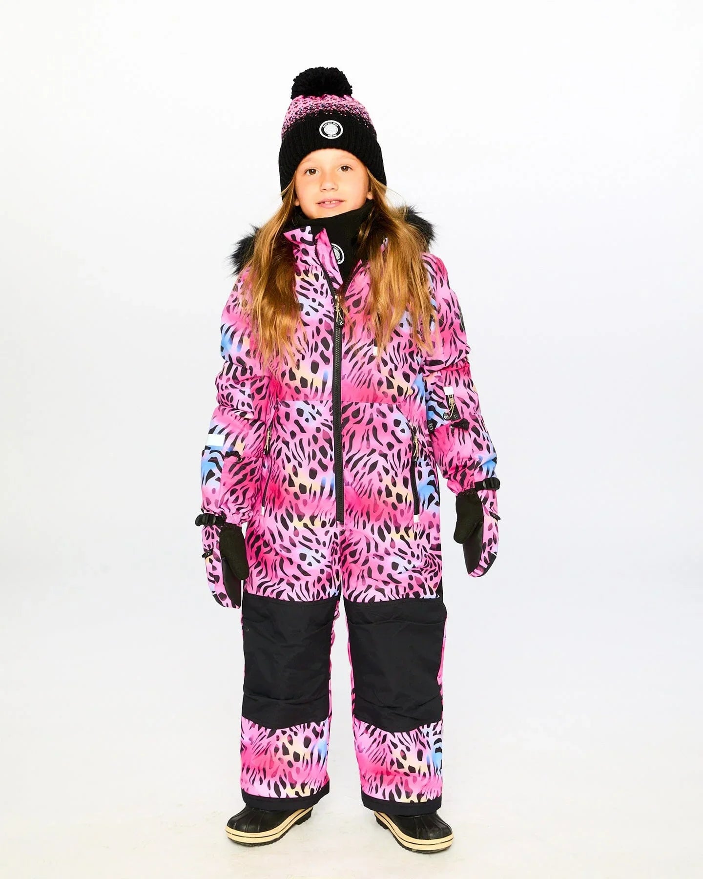 Girl in bright pink animal print snowsuit, knit winter hat, and boots at Qu!rk Boutique