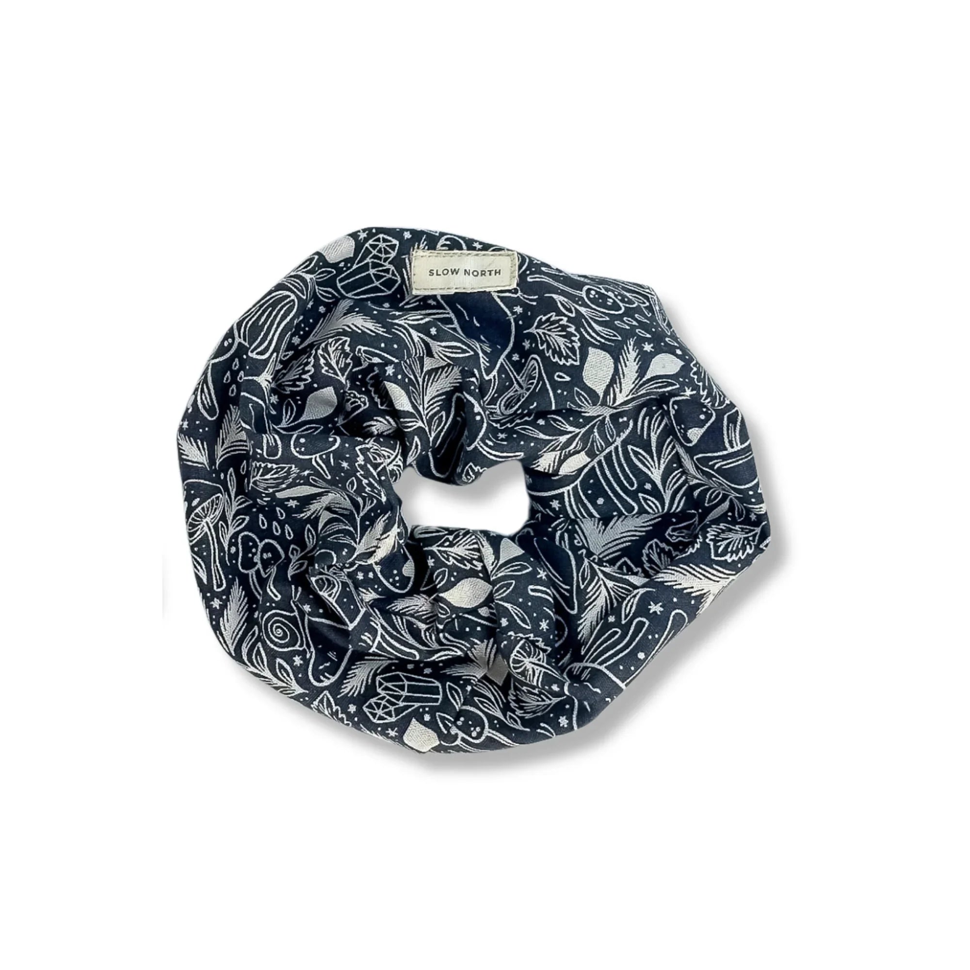 Dark blue scrunchie with white botanical and crystal patterns and Slow North label