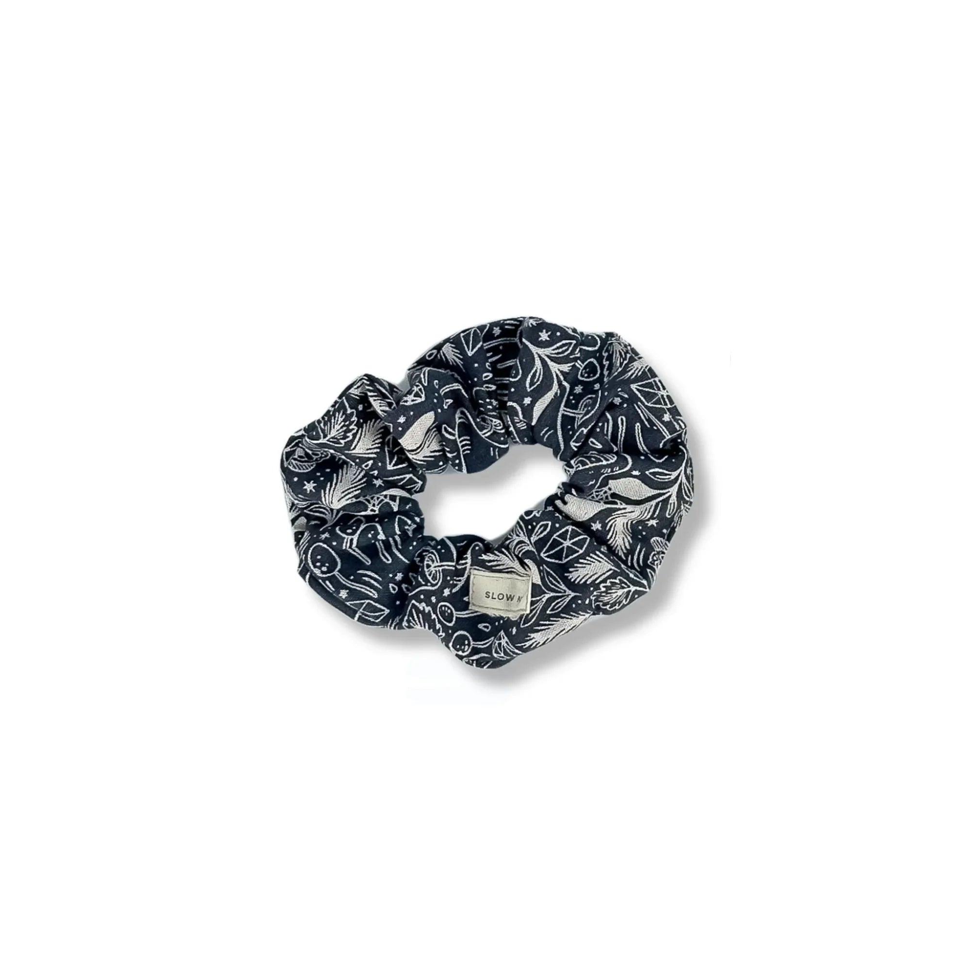 Black fabric scrunchie with white botanical and celestial patterns and SLOW label