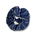 Navy blue fabric scrunchie with light pink crescent moon pattern and Slow North label