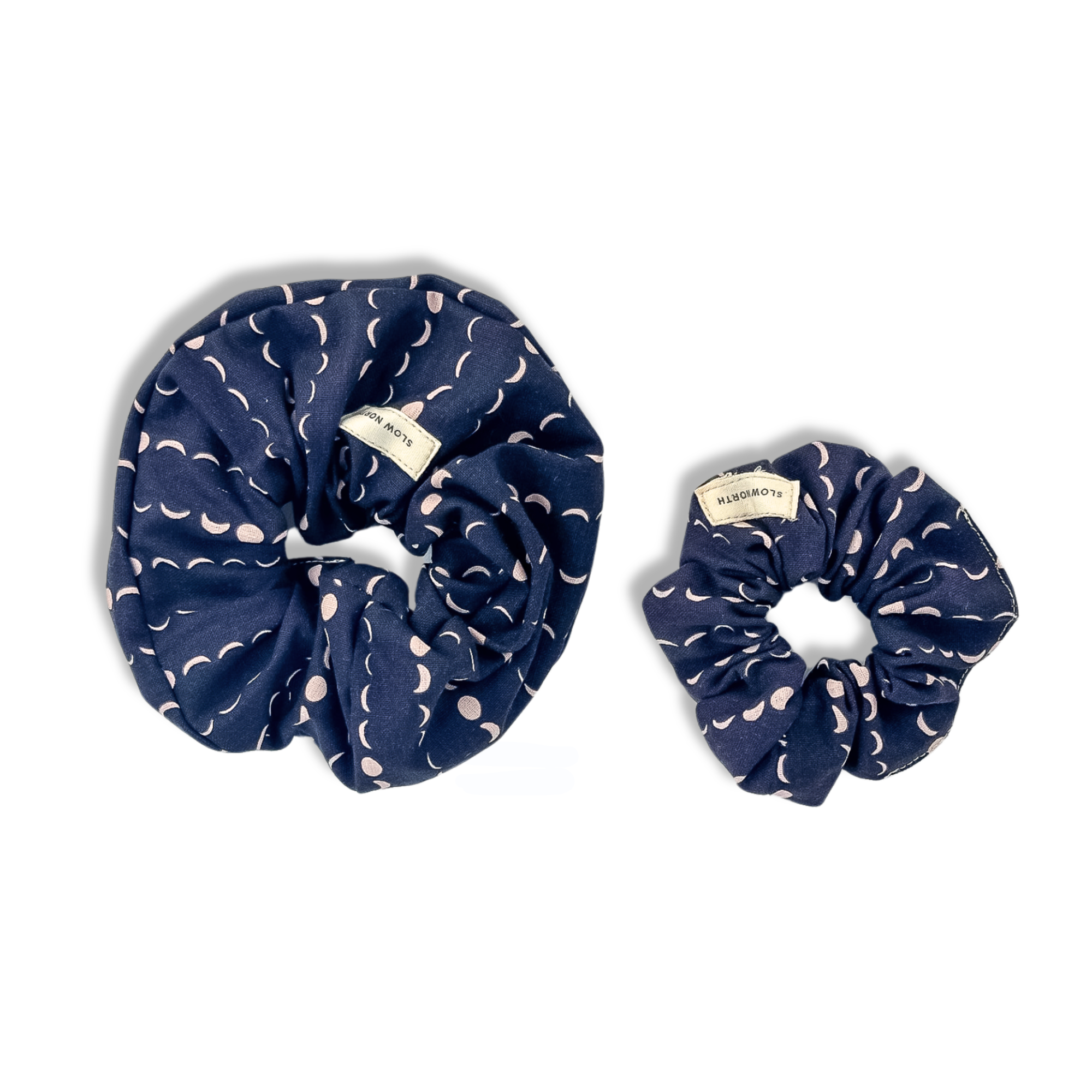 Two navy blue fabric scrunchies with pale crescent moon patterns and 'SLOW NORTH' labels on white background