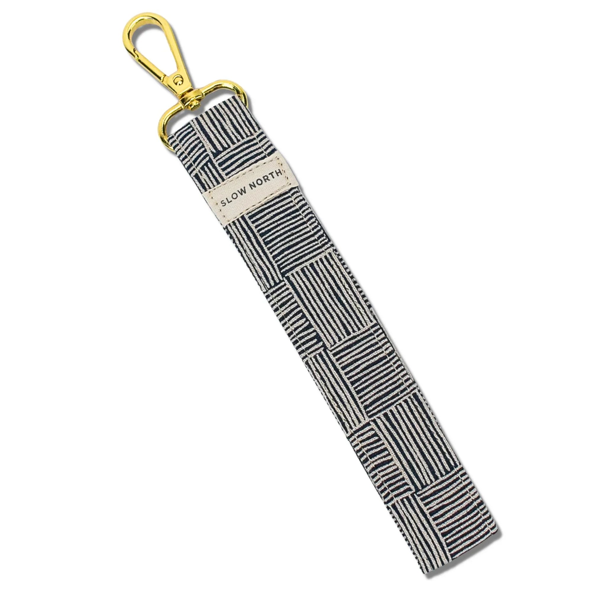 Black and white striped fabric wristlet keychain with gold clasp and Slow North label